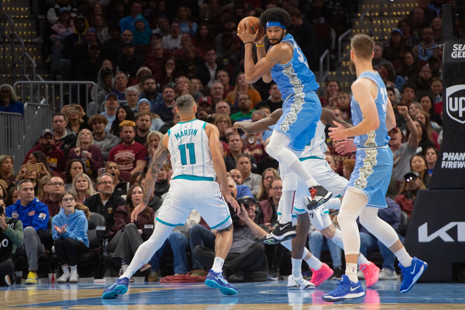 Cleveland Cavaliers' Jarrett Allen, center, grabs a rebound as Charlotte Hornets' Cody Martin (11) and Dean Wade, right, look on during the second half of an NBA basketball game in Cleveland, Sunday, Nov 17, 2024. (AP Photo/Phil Long)