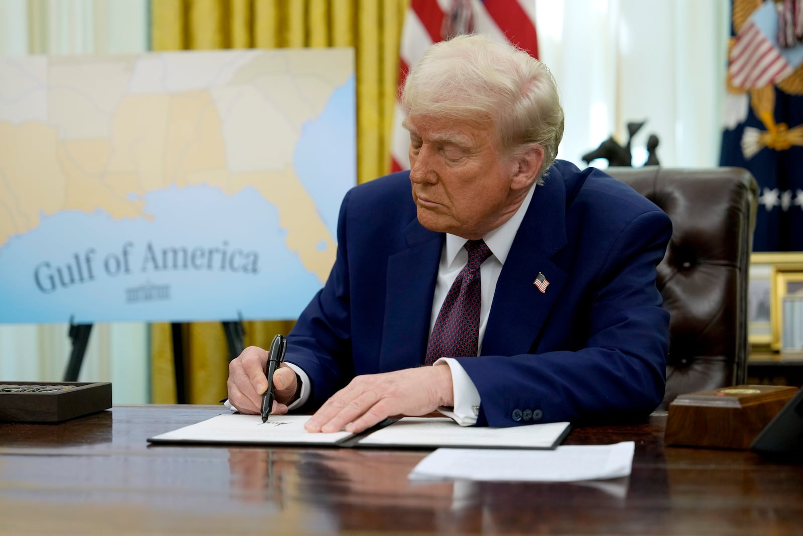 President Donald Trump signs an executive order in the Oval Office of the White House, Thursday, Feb. 13, 2025, in Washington. (AP Photo/Ben Curtis)