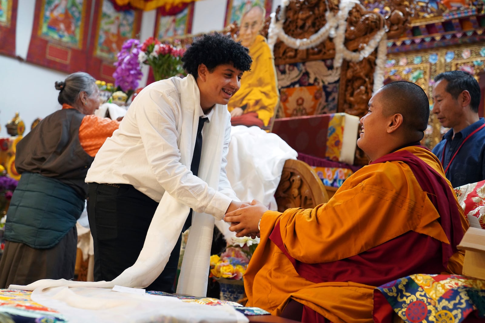 High school friends present U.S.-born Buddhist lama, Jalue Dorje, with a “khata,” the Tibetan ceremonial scarves that symbolize auspiciousness, at his 18th birthday and enthronement ceremony, in Isanti, Minn., on Saturday, Nov. 9, 2024. (AP Photo/Jessie Wardarski)