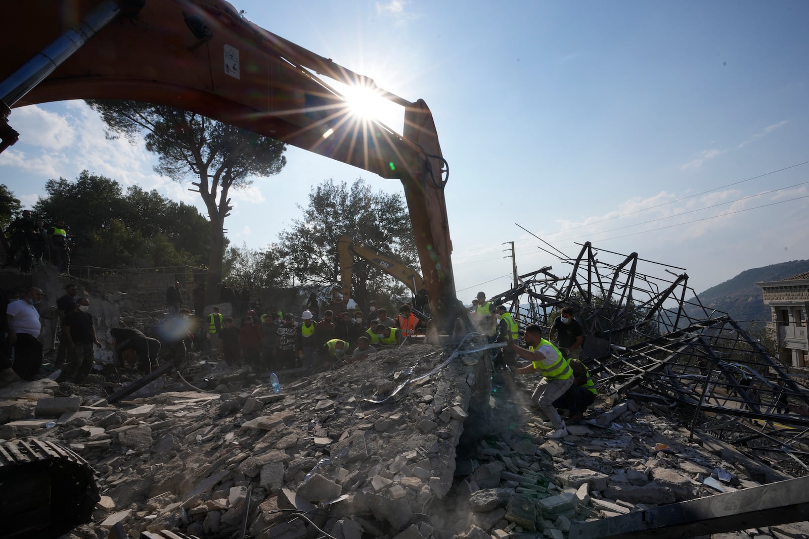 Rescue workers use an excavator to remove the rubble of a destroyed house hit in an Israeli airstrike, as they search for victims in Aalmat village, northern Lebanon, Sunday, Nov. 10, 2024. (AP Photo/Hassan Ammar)