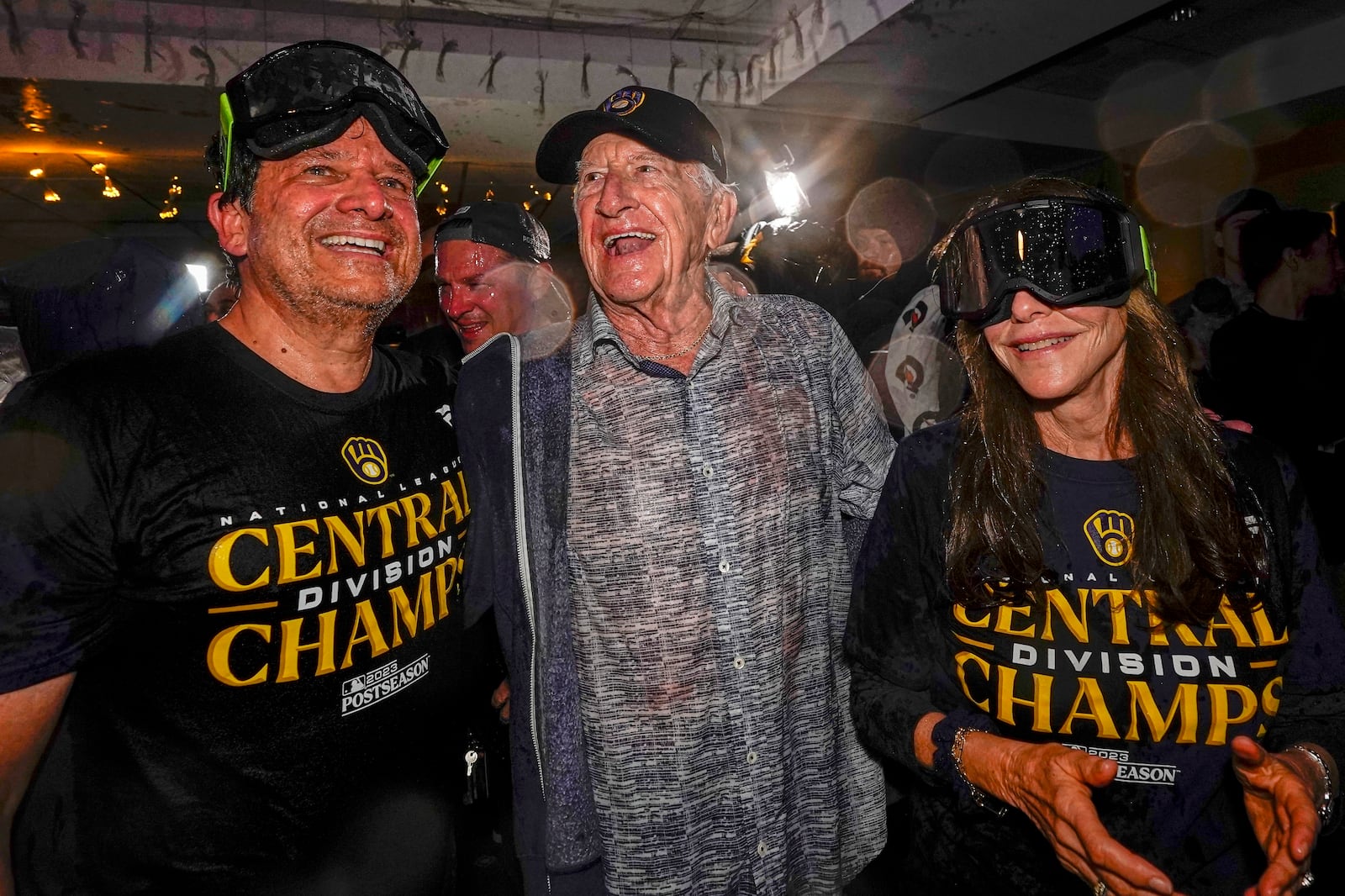 FILE - Milwaukee Brewers' owner Mark Attanasio and wife Debbie celebrate with broadcaster Bob Uecker after clinching the National League Central Division after a baseball game against the St. Louis Cardinals, Sept. 26, 2023, in Milwaukee. (AP Photo/Morry Gash)