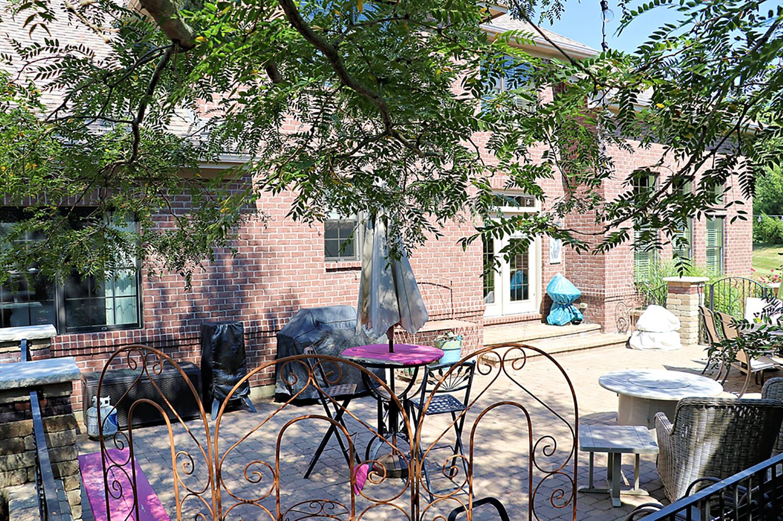 French doors with a transom open to the paver-brick patio with brick wall surround, including wrought-iron gates. Tree-lined privacy hills seclude the courtyard patio and back yard. CONTRIBUTED PHOTO BY KATHY TYLER