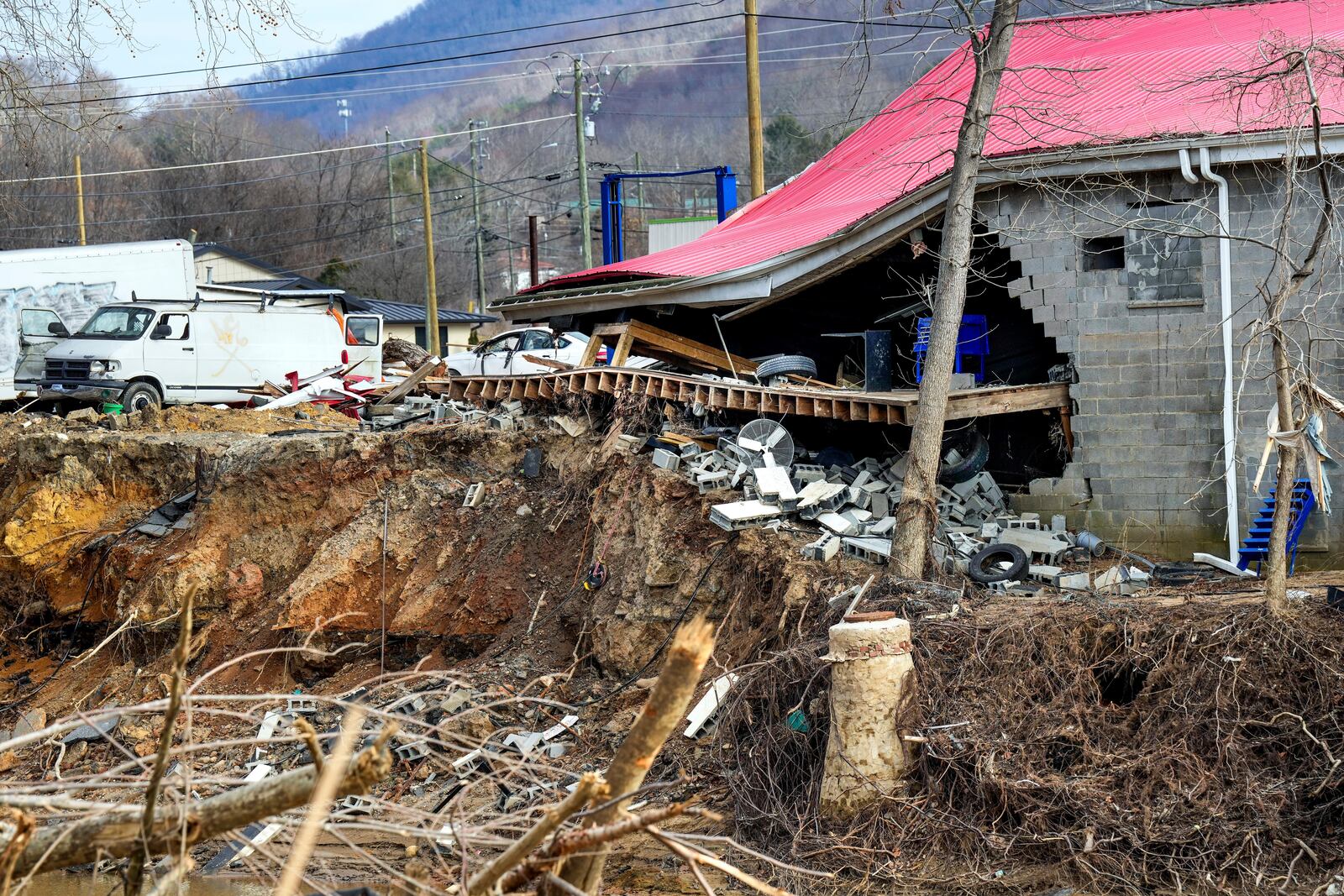 A view of a building and damaged waterfront destroyed by Hurricane Helene as seen from across the Swannanoa River adjacent to Vickie Revis' property, Wednesday, Feb. 5, 2025, in Swannanoa, N.C. (AP Photo/Kathy Kmonicek)