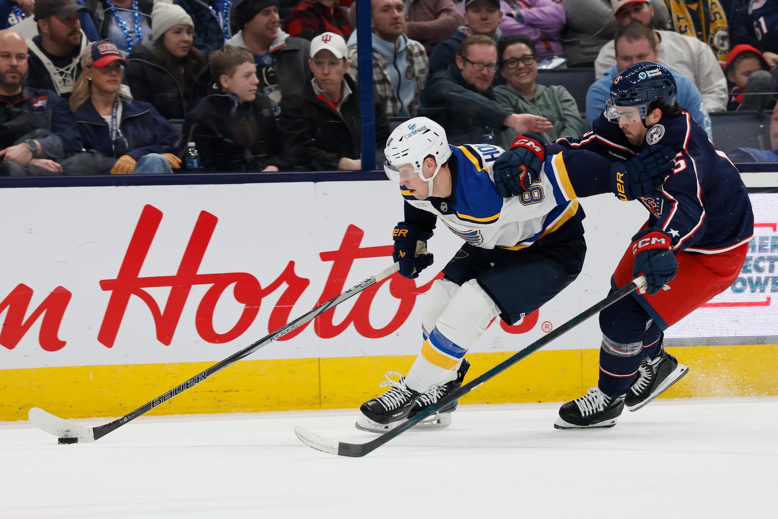 St. Louis Blues' Dylan Holloway, left, keeps the puck away from Columbus Blue Jackets' Dante Fabbro, right, during the third period of an NHL hockey game Saturday, Jan. 4, 2025, in Columbus, Ohio. (AP Photo/Jay LaPrete)