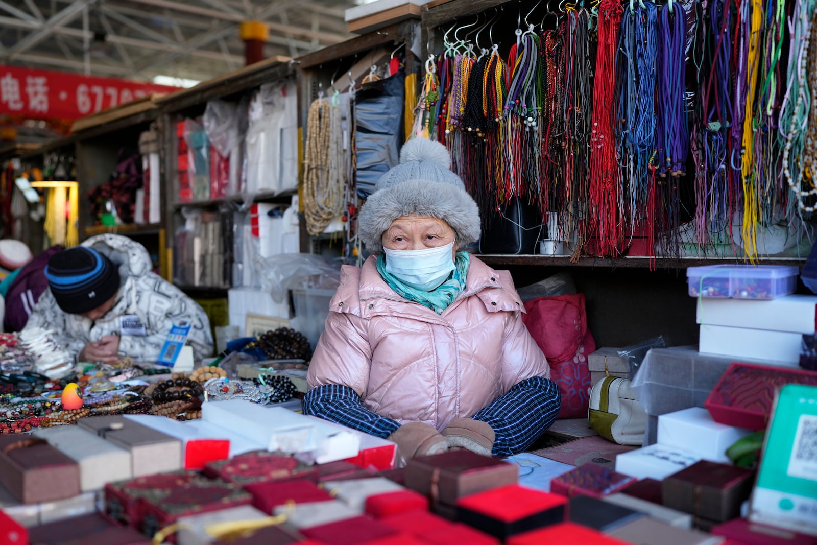 A senior woman waits for customers at a market in Beijing, Thursday, Jan. 16, 2025. (AP Photo/Aaron Favila)