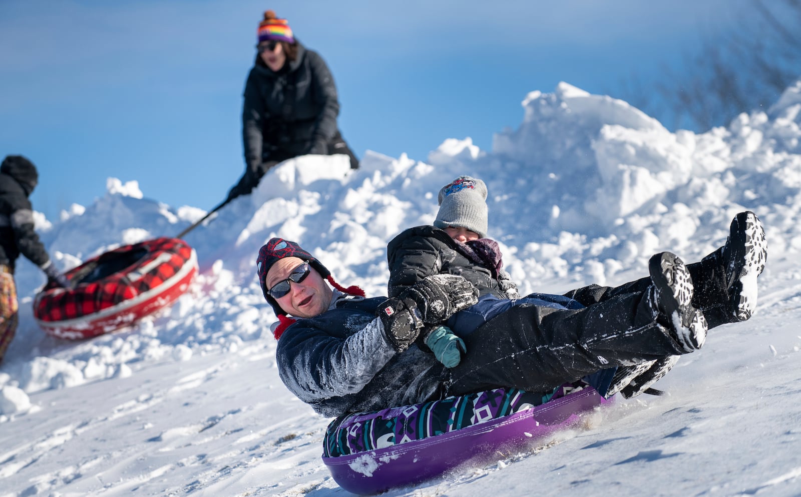 Kyle Foss holds his son Kasen as they slide behind Sherwood Heights Elementary School in Auburn, Maine, Monday, Jan. 20, 2025, with their family and friends. (Russ Dillingham/Sun Journal via AP)