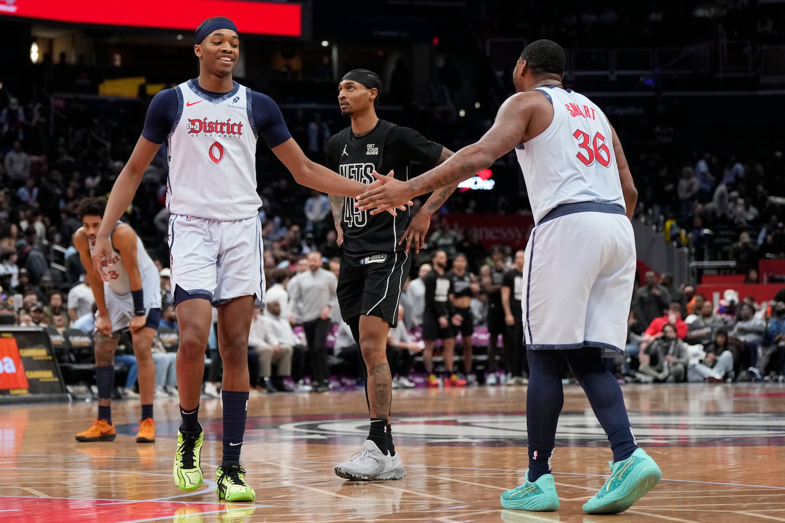 Washington Wizards guards Bilal Coulibaly (0) and Marcus Smart (36) high-five as Brooklyn Nets guard Keon Johnson looks on during the second half of an NBA basketball game, Monday, Feb. 24, 2025, in Washington. (AP Photo/Jess Rapfogel)