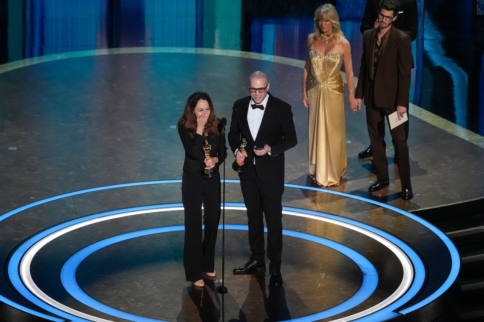 Shirin Sohani, left, and Hossein Molayemi accept the award for best animated short for "In the Shadow of the Cypress" during the Oscars on Sunday, March 2, 2025, at the Dolby Theatre in Los Angeles. Goldie Hawn, second right, and Andrew Garfield look on from right. (AP Photo/Chris Pizzello)