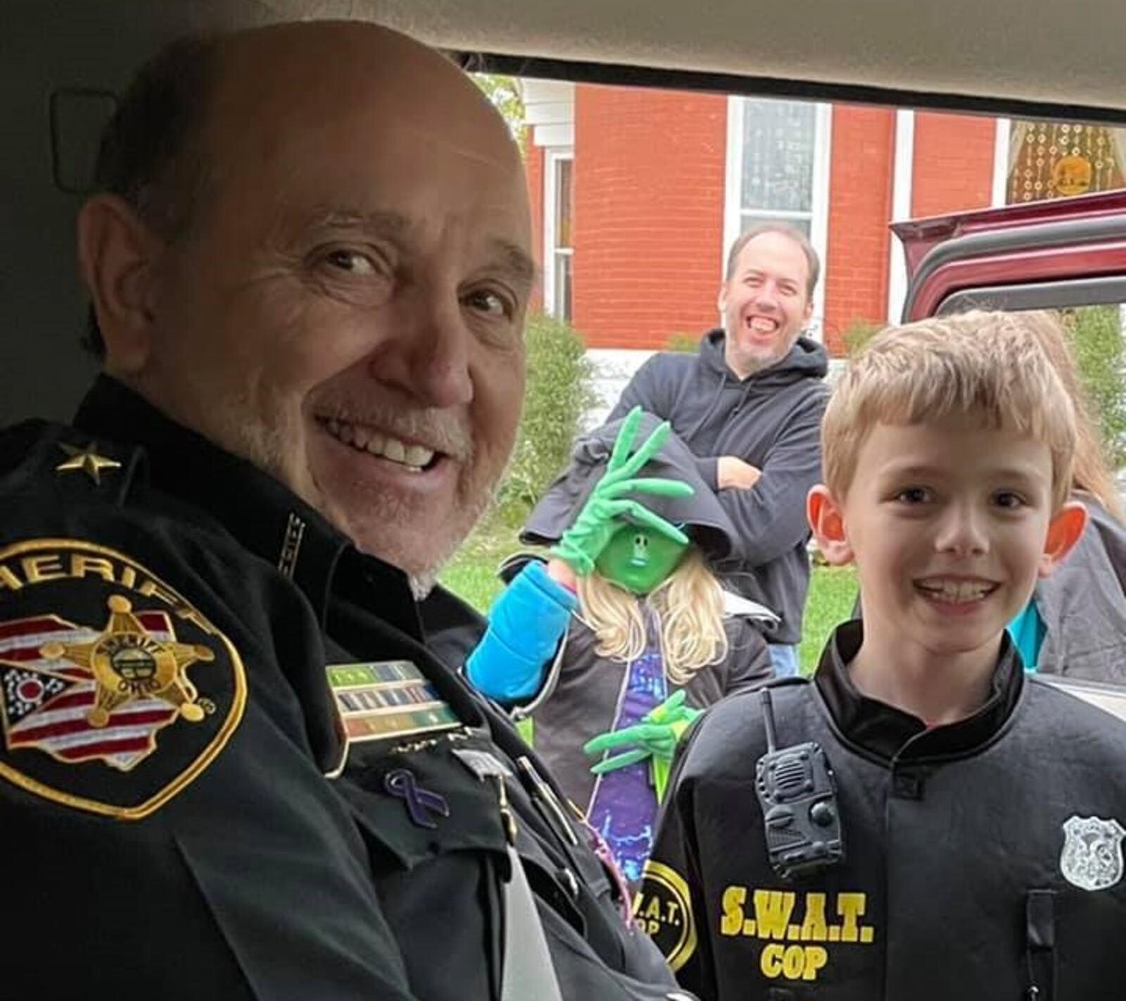 Greene County Sheriff Gene Fischer meets a young law enforcement officer trick-or-treating on Halloween, Sunday, Oct. 31, 2021.