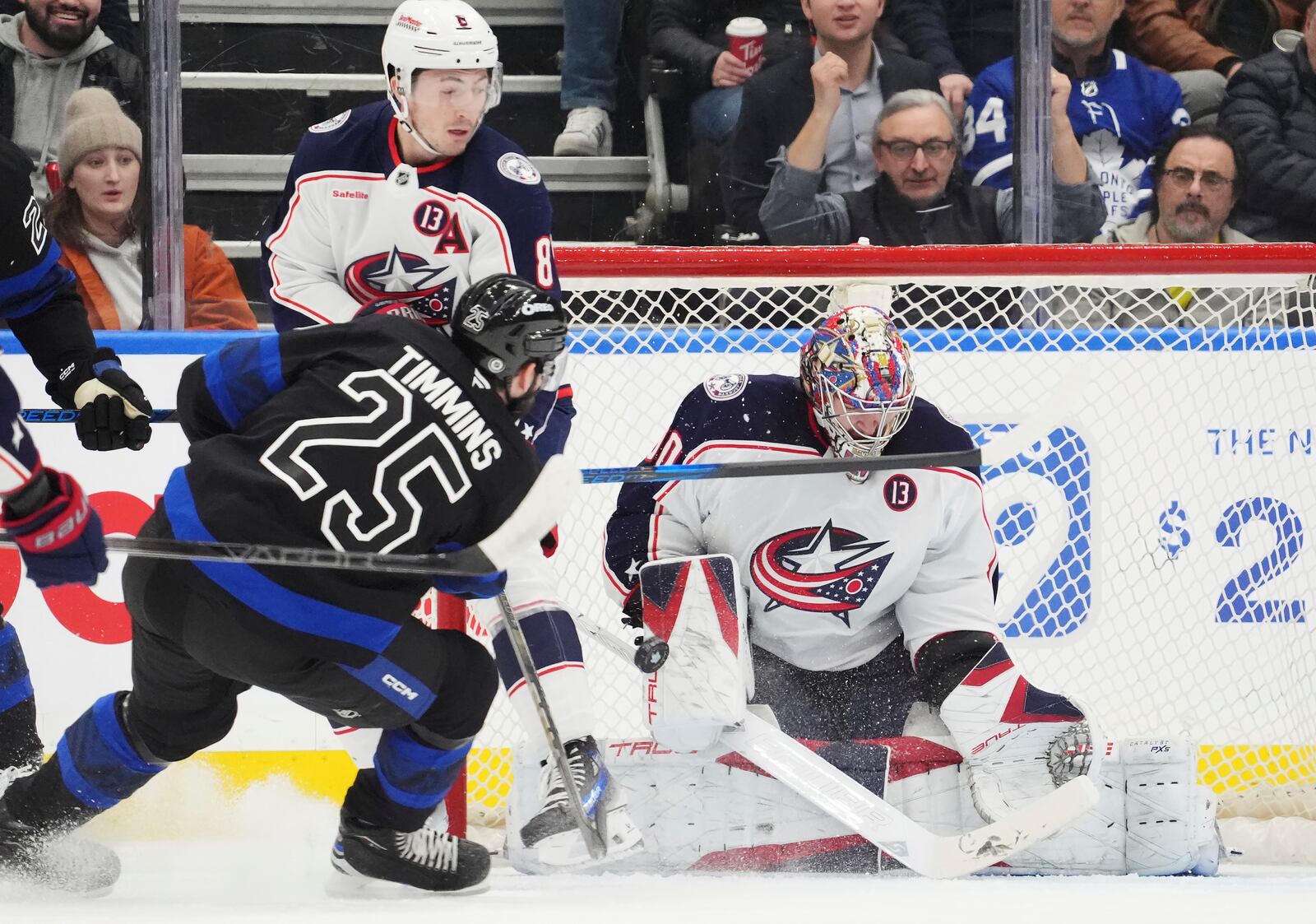 Columbus Blue Jackets goaltender Elvis Merzlikins (90) makes a save on Toronto Maple Leafs' Conor Timmins (25) as Blue Jackets' Zach Werenski (8) defends during first period NHL hockey action in Toronto on Wednesday, Jan. 22, 2025. (Frank Gunn/The Canadian Press via AP)