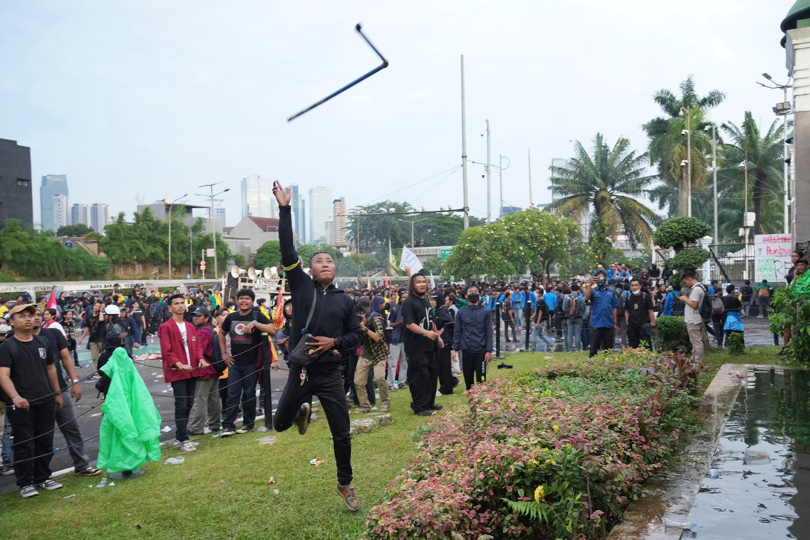 A protester throws an object toward riot police officers during a rally outside the parliament in Jakarta, Indonesia, Thursday, March 20, 2025, against the passing of a controversial revision of a military law that will allow military officers to serve in more government posts without resigning from the armed forces. (AP Photo/Tatan Syuflana)