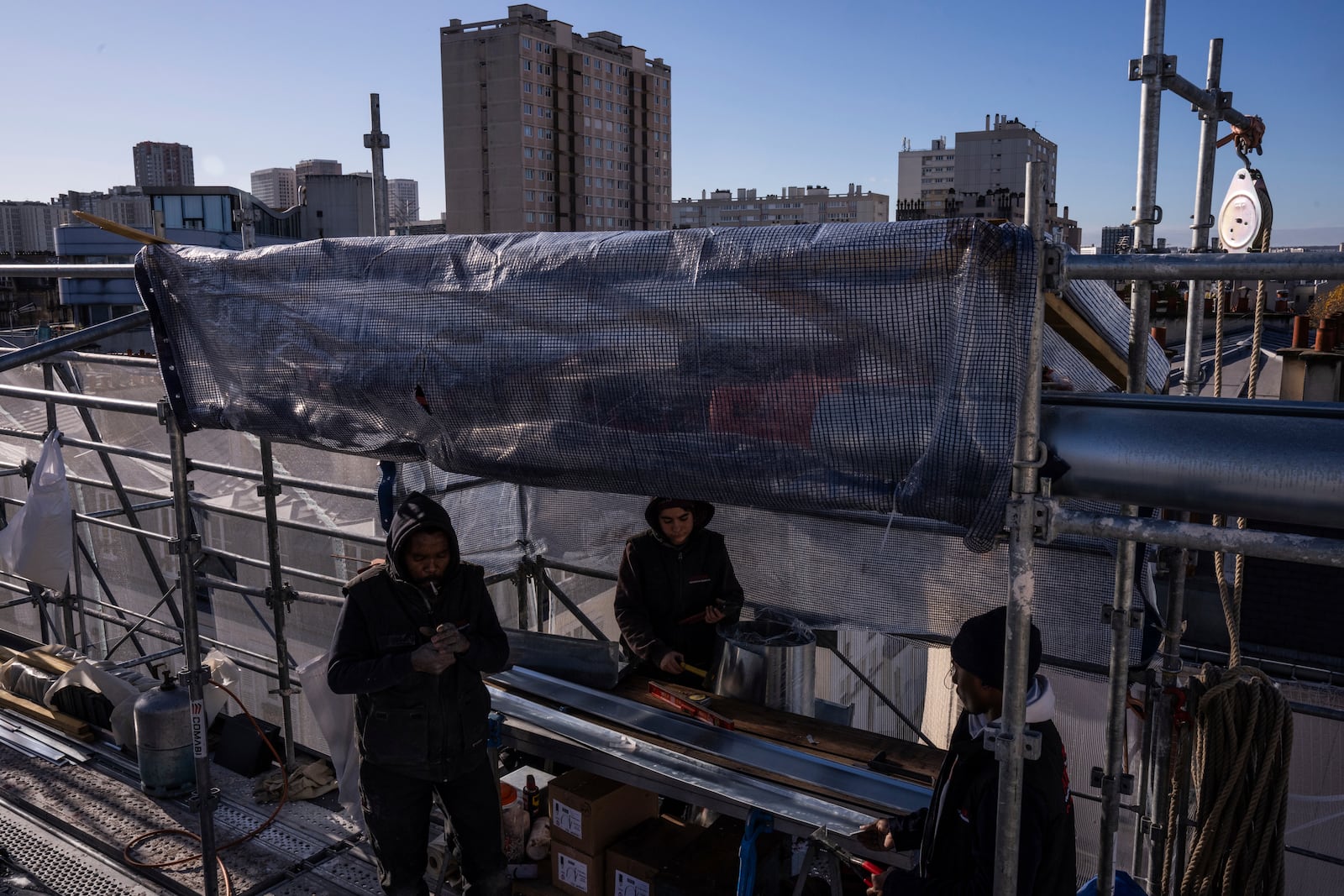 Roofers work on zinc sheets on the roof of a building in Paris, Wednesday, Nov. 20, 2024. (AP Photo/Louise Delmotte)