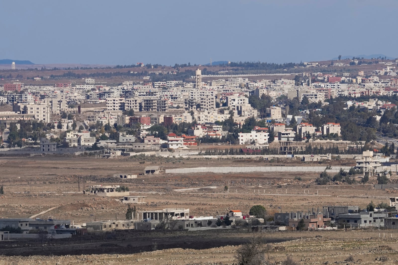 A Syrian village stands on the buffer zone situated between the so-called Alpha and Bravo Lines which separates Syria and Israel, photographed from the Israeli-controlled Golan Heights, Friday, Dec. 13, 2024. (AP Photo/Matias Delacroix)