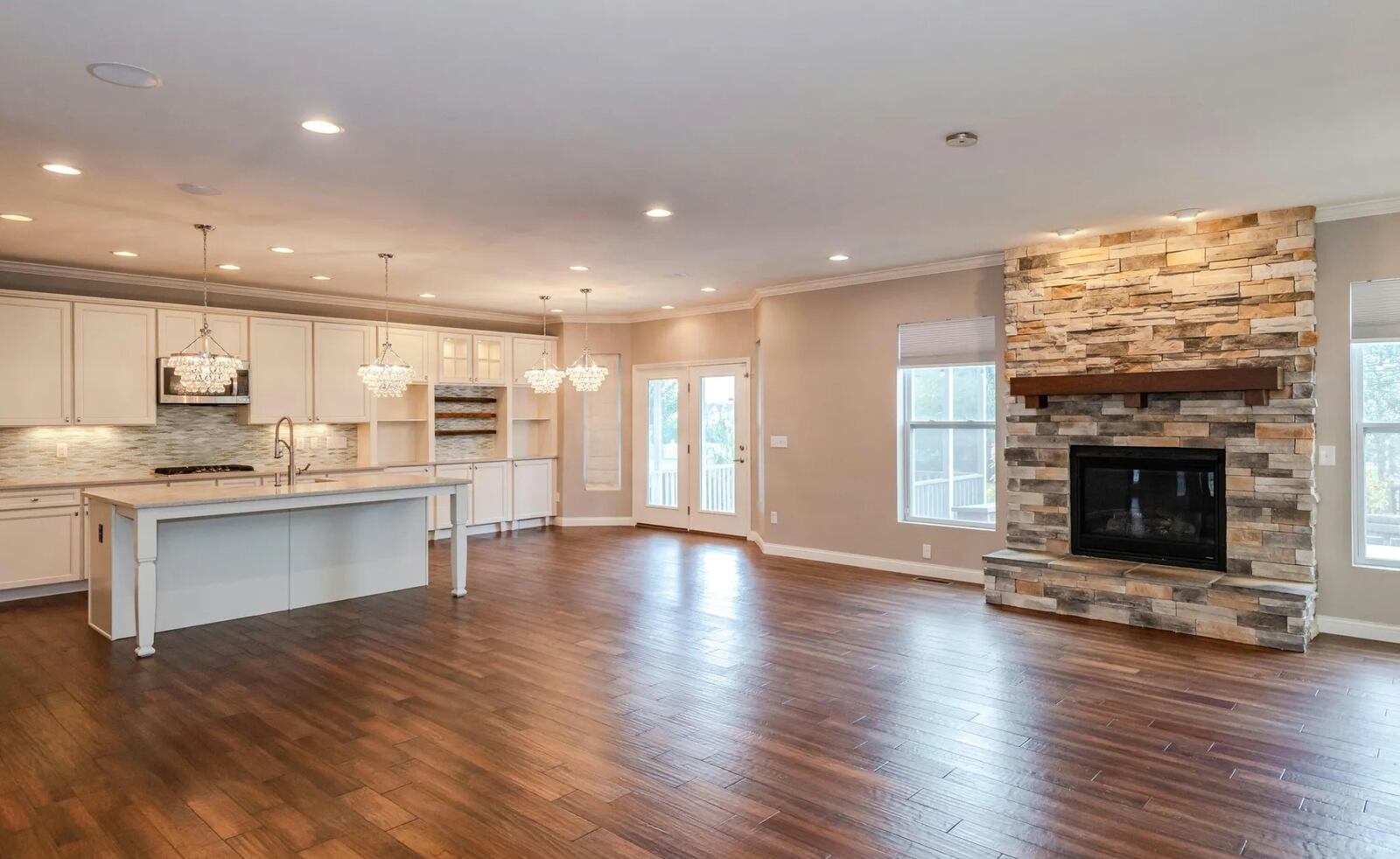 Flanked by windows, a stack-stone gas fireplace in the great room has a wood-beam mantel and raised stone hearth. CONTRIBUTED