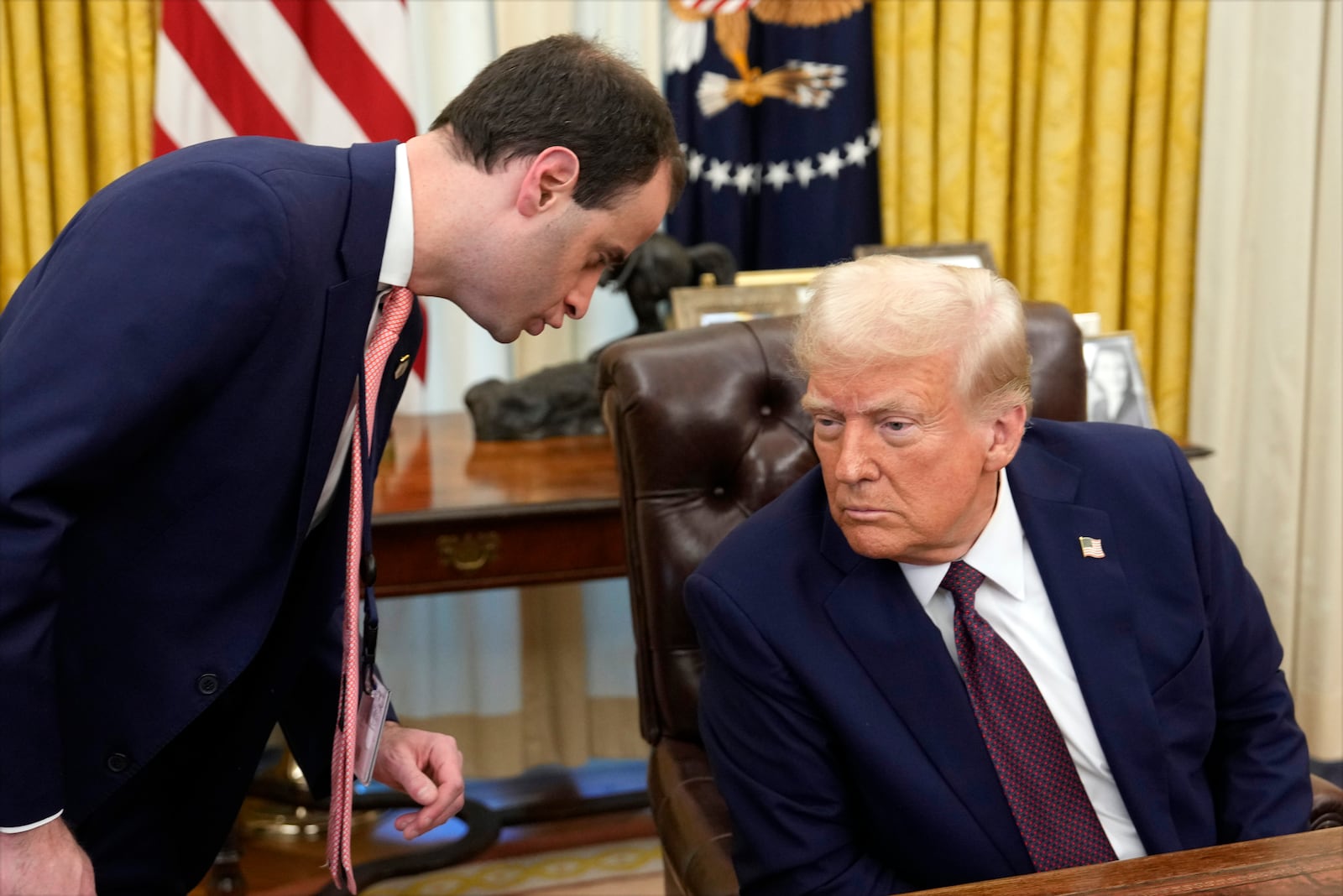 White House staff secretary Will Scharf talks with President Donald Trump after he signed executive orders in the Oval Office of the White House, Thursday, Jan. 23, 2025, in Washington. (AP Photo/Ben Curtis)