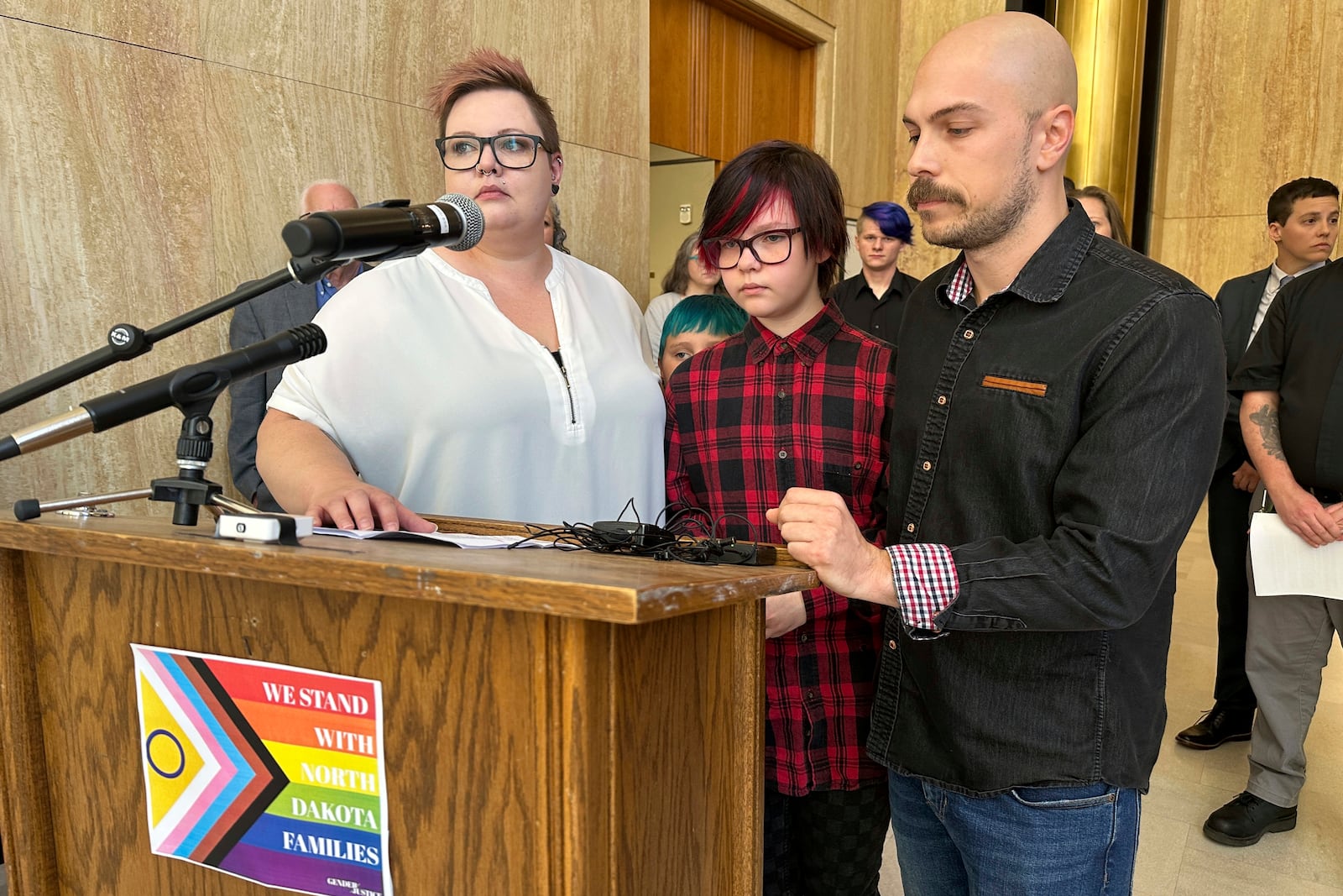 FILE - Parents Devon and Robert Dolney, of Fargo, N.D., stand with their 12-year-old child, Tate, center, during a news conference at the state Capitol in Bismarck, N.D., Sept. 14, 2023. (AP Photo/Jack Dura, File)