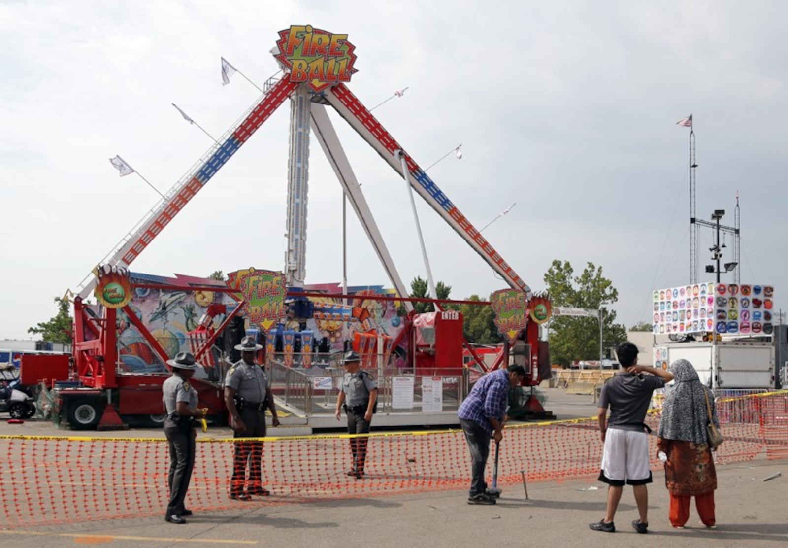 Passers by look at the Fire Ball ride as Ohio State Highway Patrol troopers stand guard at the Ohio State Fair Thursday, July 27, 2017, in Columbus, Ohio. The fair opened Thursday but its amusement rides remained closed one day after Tyler Jarrell, 18, was killed and seven other people were injured when the thrill ride broke apart and flung people into the air. AP Photo/Jay LaPrete