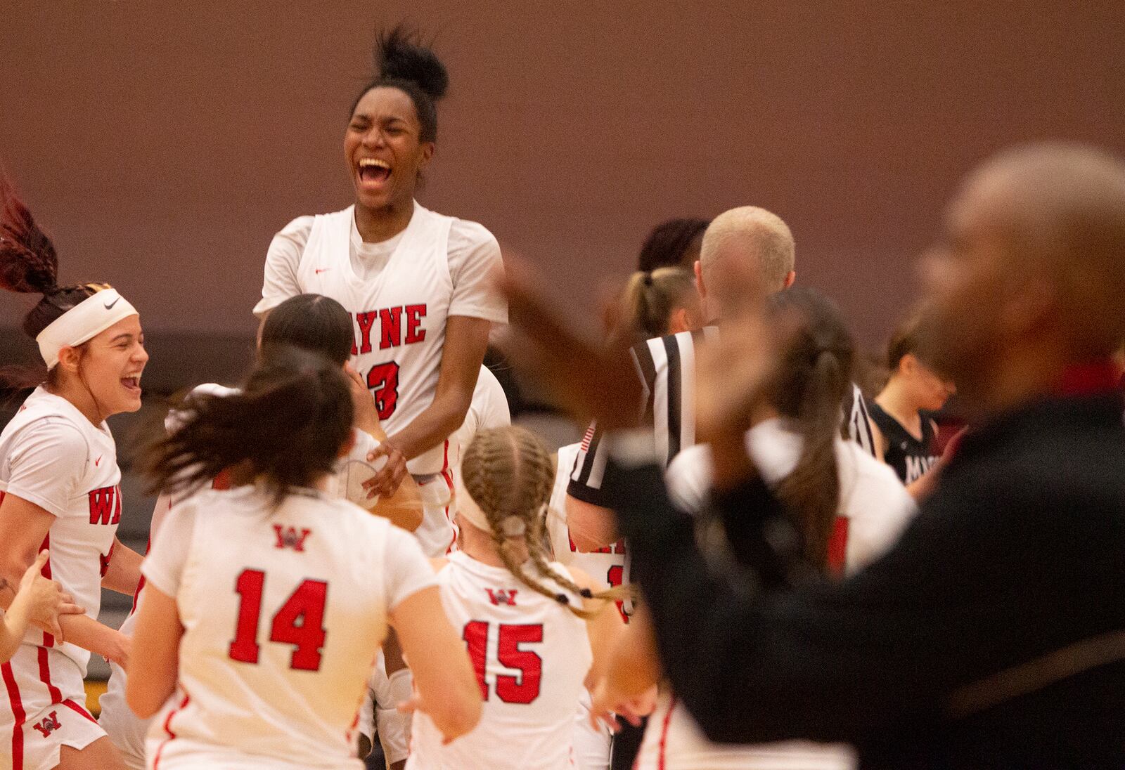 Wayne players lift teammate Bree Hall during their postgame celebration while head coach Travis Trice claps in the foreground. The Warriors defeated Mason 55-51 to advance to the Division I regional final. Jeff Gilbert/CONTRIBUTED