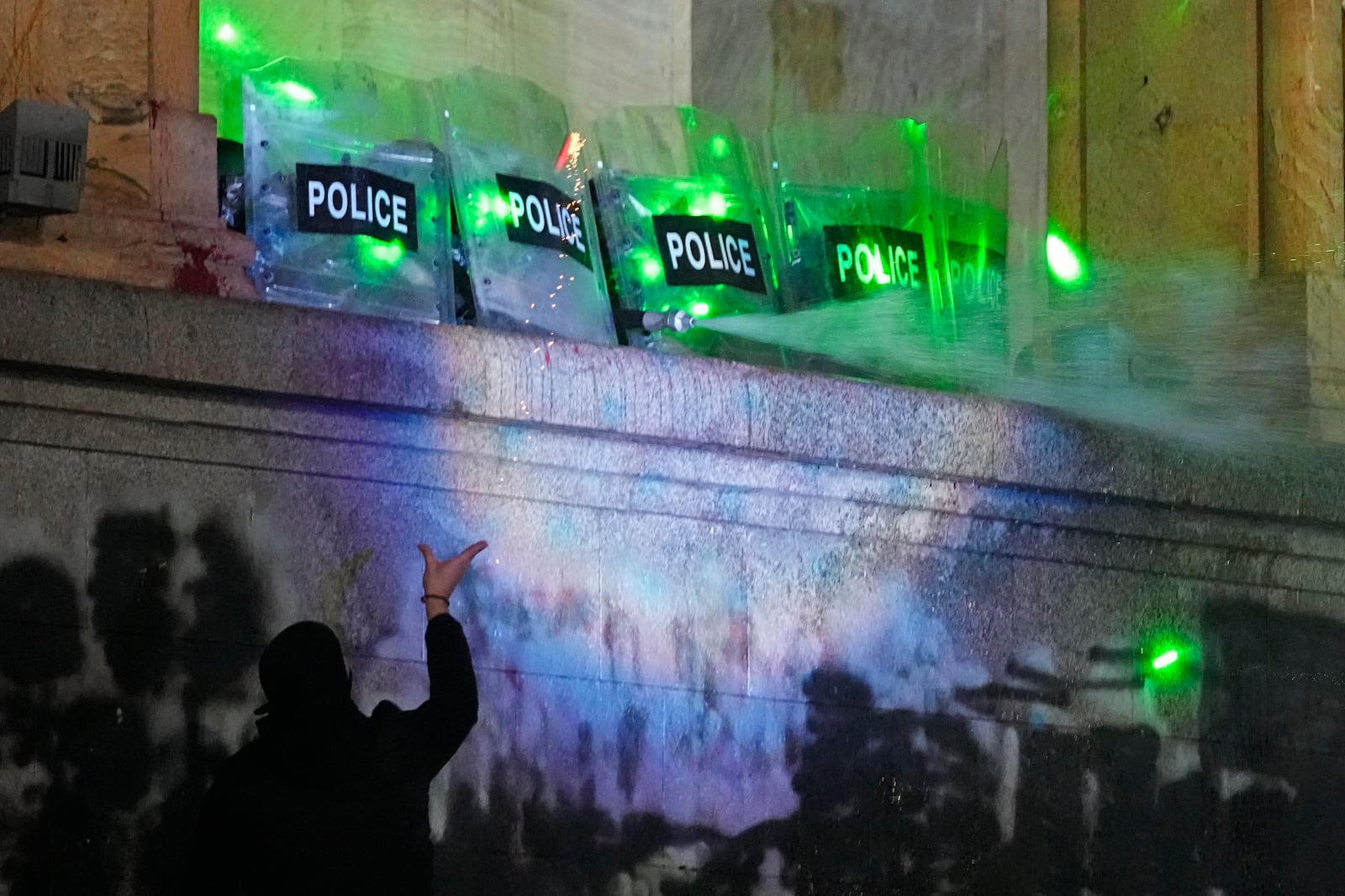 Demonstrators stand under running water from a fire-pump used by police rallying outside the parliament to continue protests against the government's decision to suspend negotiations on joining the European Union in Tbilisi, Georgia, on Tuesday, Dec. 3, 2024. (AP Photo/Pavel Bednyakov)