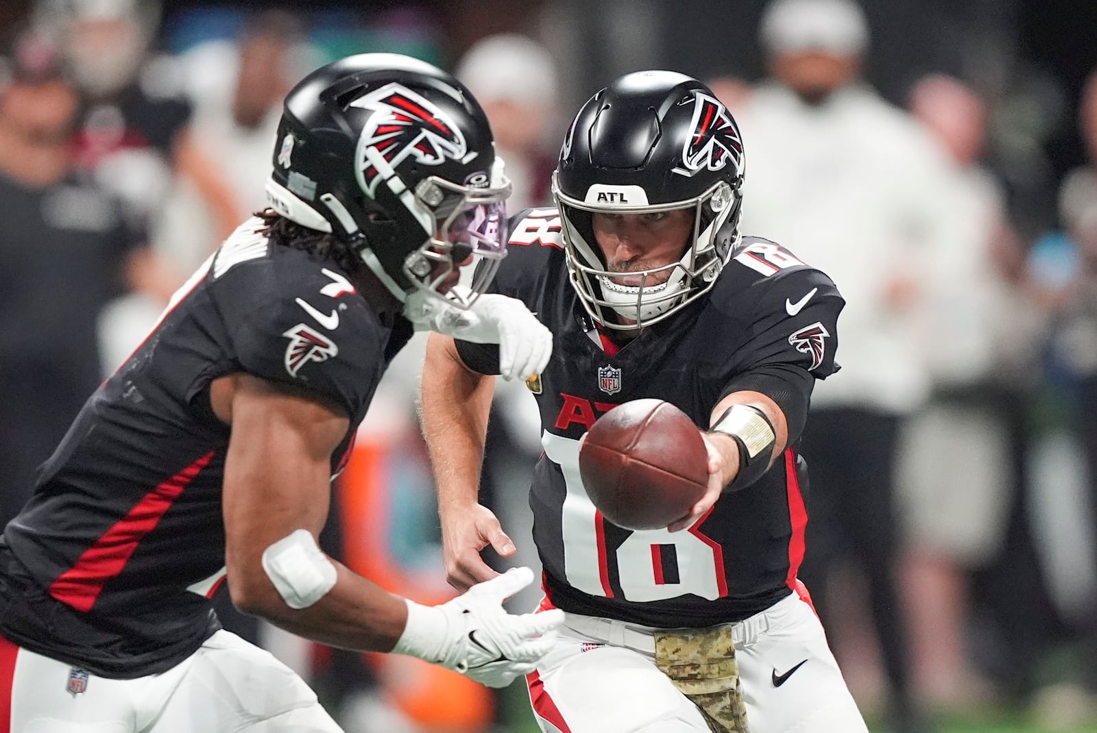 Atlanta Falcons quarterback Kirk Cousins (18) hands off to running back Bijan Robinson (7) during the first half of an NFL football game against the Dallas Cowboys, Sunday, Nov. 3, 2024, in Atlanta. (AP Photo/ Brynn Anderson)