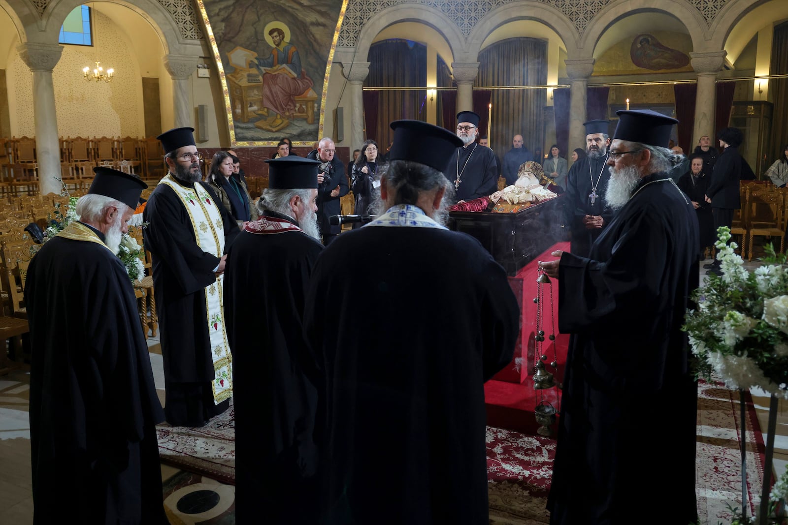 Greek Orthodox priests stand next to the casket of the late Archbishop Anastasios of Tirana, Durres and All Albania during a religious ceremony, a day before his funeral, inside the Cathedral of the Resurrection of Christ, in Tirana, Albania, Wednesday, Jan. 29, 2025. (AP Photo/Vlasov Sulaj)