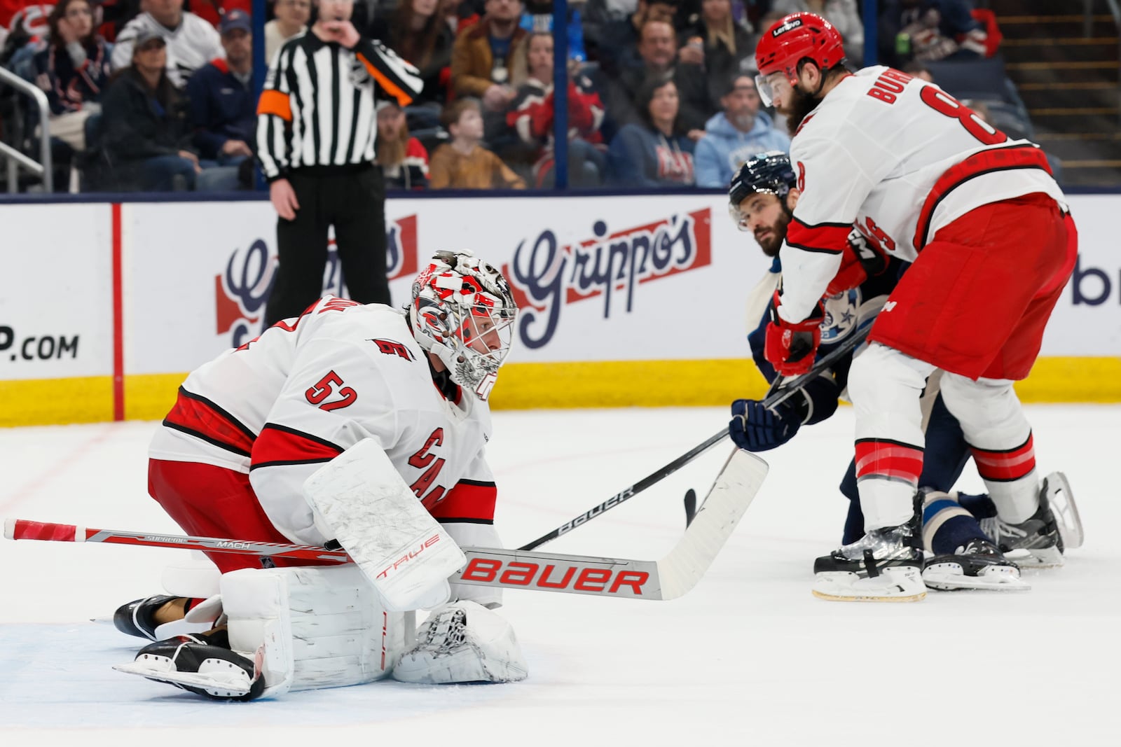 Carolina Hurricanes' Pyotr Kochetkov, left, covers the puck as teammate Brent Burns, right, and Columbus Blue Jackets' Kirill Marchenko fight for position during the second period of an NHL hockey game Tuesday, Dec. 31, 2024, in Columbus, Ohio. (AP Photo/Jay LaPrete)