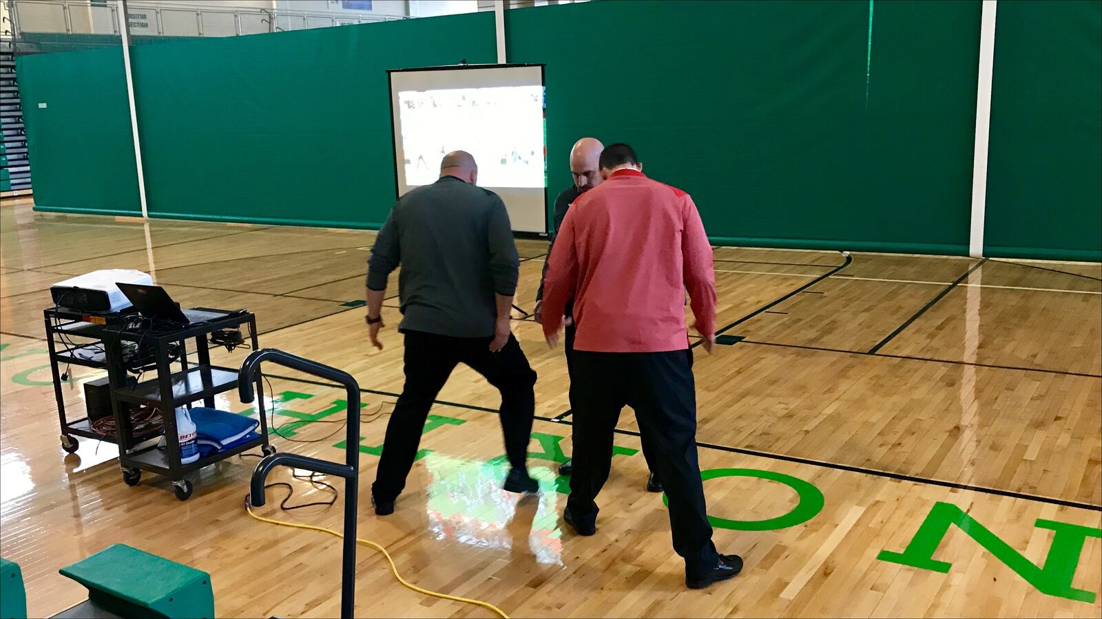 Ohio State offensive line coach Greg Studwara (left) and assistants demonstrate a combo block at a clinic at Northmont High School.