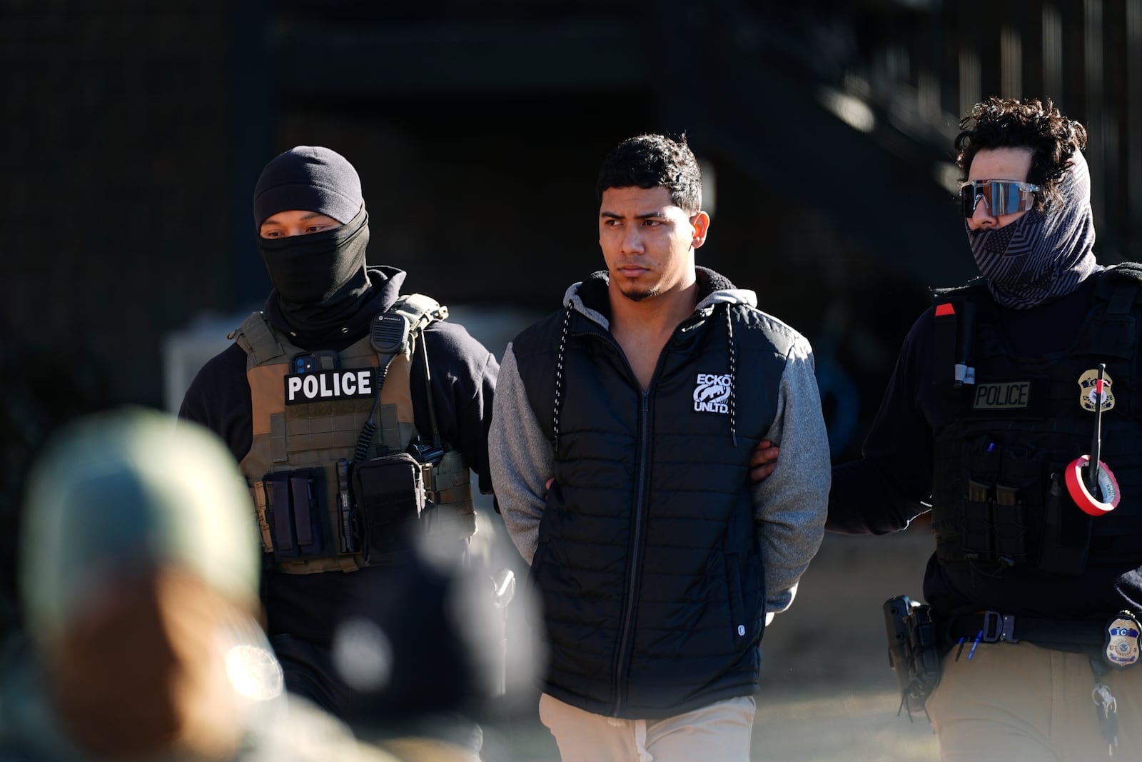 Law officials escort a man from an apartment to a waiting utility vehicle for transport during a raid Wednesday, Feb. 5, 2025, in east Denver. (AP Photo/David Zalubowski)