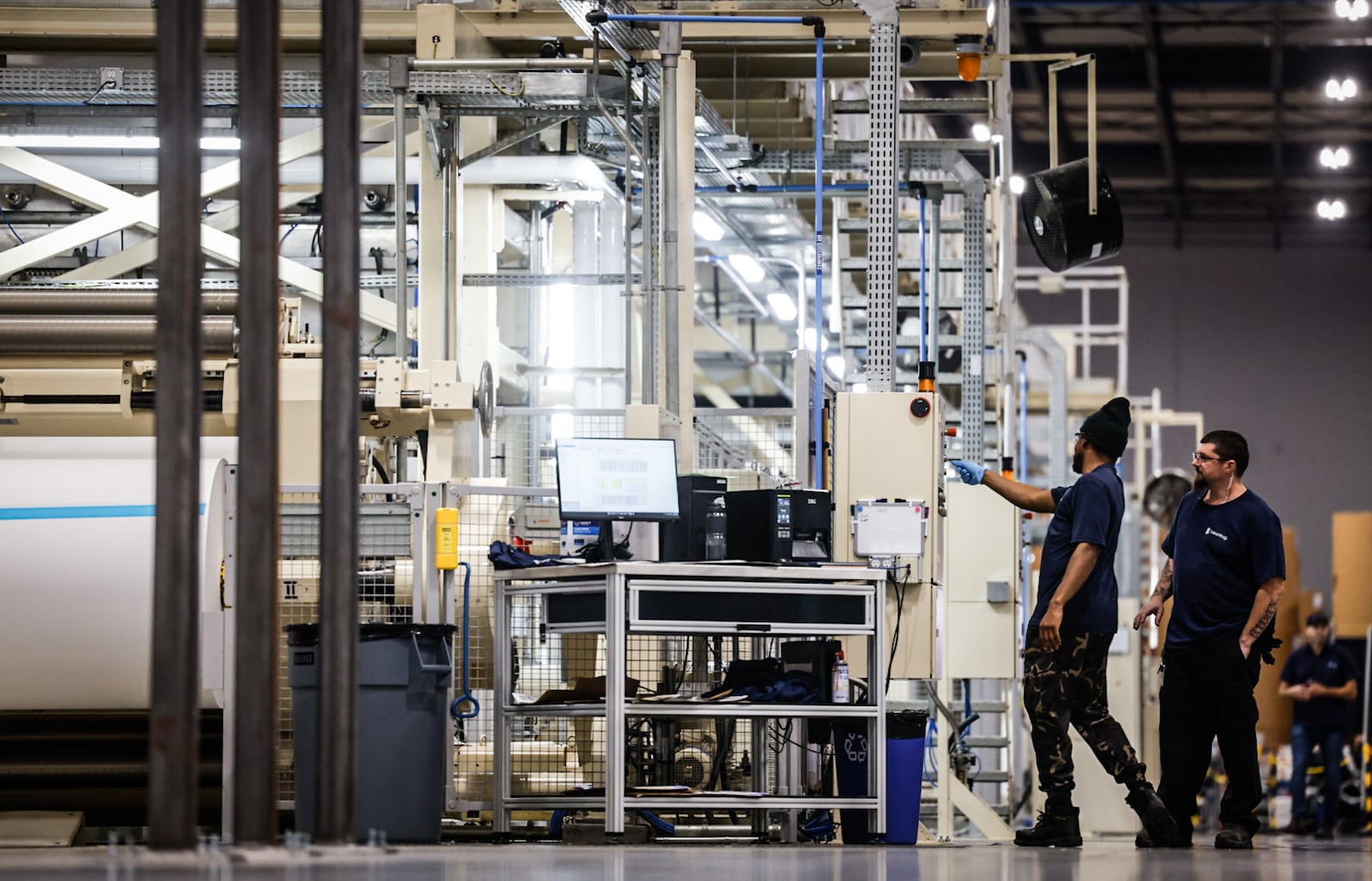 Beontag employees operate a large machine that adds adhesive to paper used to make product labels. JIM NOELKER/STAFF