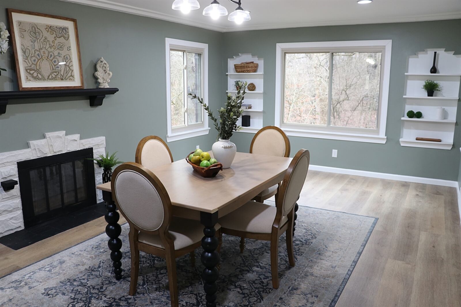 In this room, two artwork niches with open shelves flank a picture window with views of the woods.