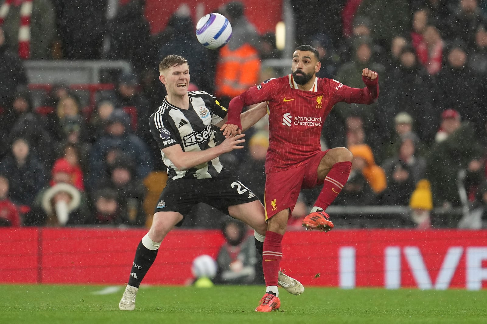 Newcastle's Lewis Hall, left, challenges Liverpool's Mohamed Salah during the English Premier League soccer match between Liverpool and Newcastle United at Anfield in Liverpool, Wednesday, Feb. 26, 2025. (AP Photo/Jon Super)