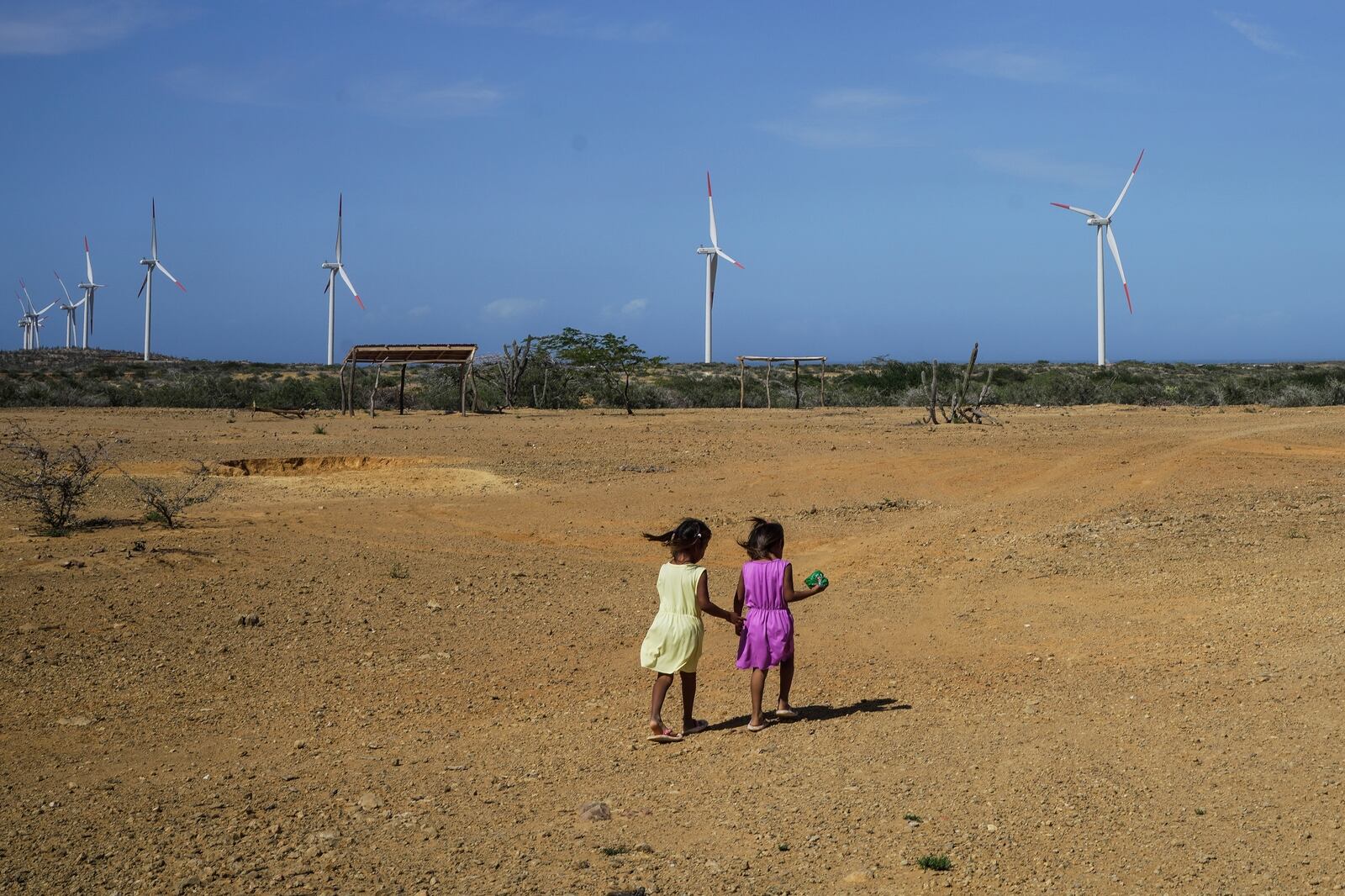 Two girls from the Wayuu Indigenous community play near a wind farm on the outskirts of Cabo de la Vela, Colombia, Friday, Feb. 7, 2025. (AP Photo/Ivan Valencia)