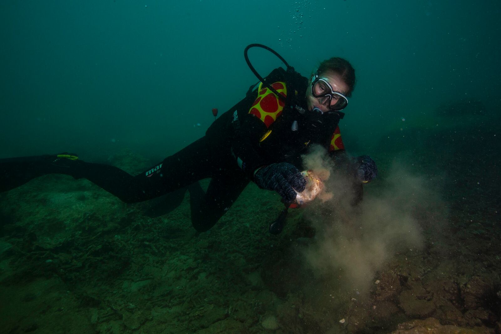 Alexandra Dudukalova collects an aluminum can off the coast of Hon Mot Island on Feb. 7, 2025, in Nha Trang, Vietnam. (AP Photo/Yannick Peterhans)