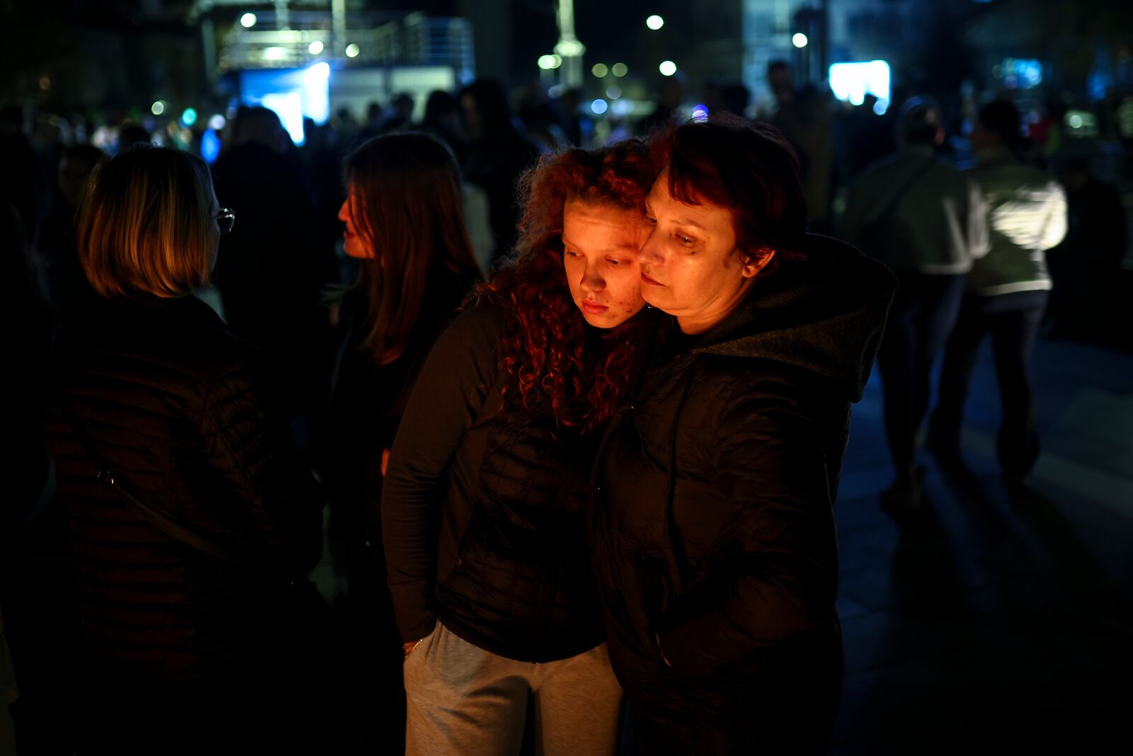 People hug as they wait in lines to light candles in the town of Kocani, North Macedonia, Sunday, March 16, 2025, following a massive fire in the nightclub early Sunday. (AP Photo/Armin Durgut)