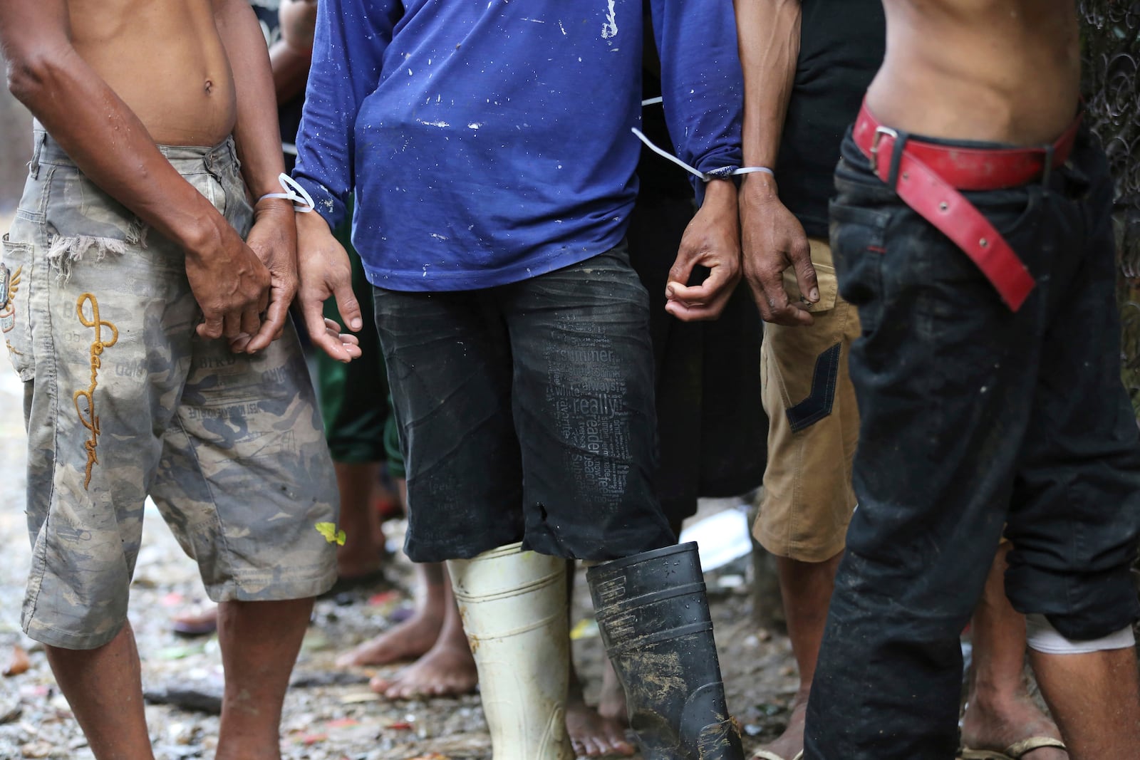 FILE- Filipino men have plastic zip ties on their wrists following a police raid at an alleged drug den as part of the continuing "War on Drugs" campaign of Philippine President Rodrigo Duterte near the Payatas dumpsite in suburban Quezon city, north of Manila, Philippines, Wednesday, Oct. 5, 2016. (AP Photo/Aaron Favila, File)