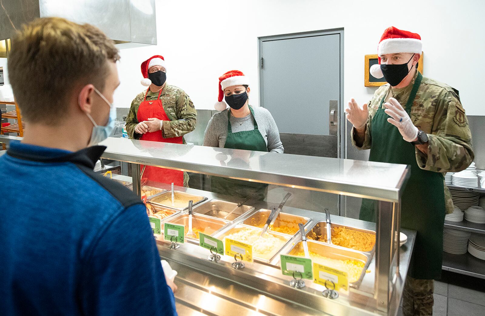 Col. Patrick Miller (center left), 88th Air Base Wing and installation commander; his wife, Beth; and Chief Master Sgt. Jason Shaffer, 88 ABW command chief; serve Christmas dinner to Airman 1st Class Nathaniel Tillman on Dec. 16 in Pitsenbarger Dining Facility at Wright-Patterson Air Force Base. Miller and Shaffer faced a series of challenges and triumphs the past two years as they maintained base operations during COVID-19 restrictions. U.S. AIR FORCE PHOTO/R.J. ORIEZ