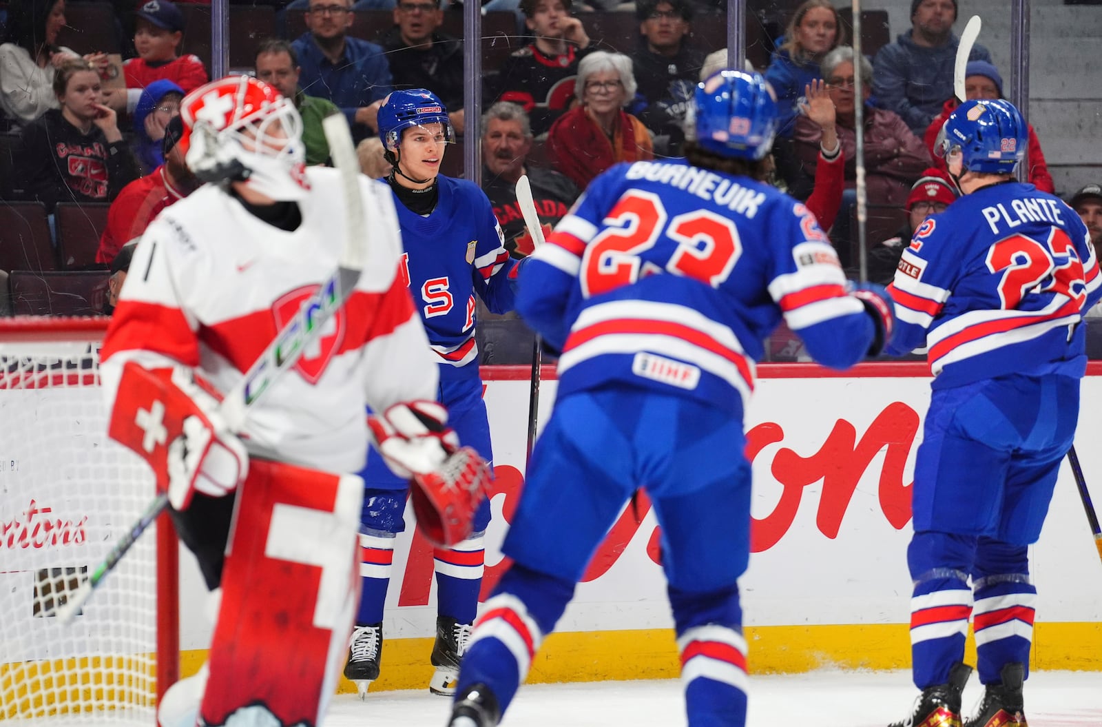 USA forward Brandon Svoboda (8) celebrates his goal with forward Austin Burnevik (23) and forward Max Plante (22) as Switzerland goaltender Christian Kirsch (1) looks on during the first period of a quarterfinal match at the IIHF World Junior Hockey Championship in Ottawa, Ontario Thursday, Jan. 2, 2025. (Sean Kilpatrick/The Canadian Press via AP)