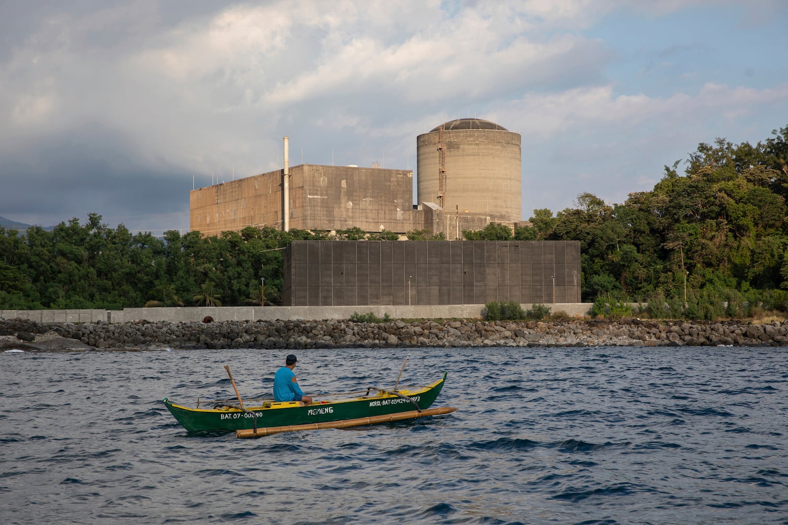 A fisherman tries to catch fish in the waters of the West Philippine Sea while passing the Bataan Nuclear Power Plant on Sunday, Jan. 19, 2025. (AP Photo/Anton L. Delgado)