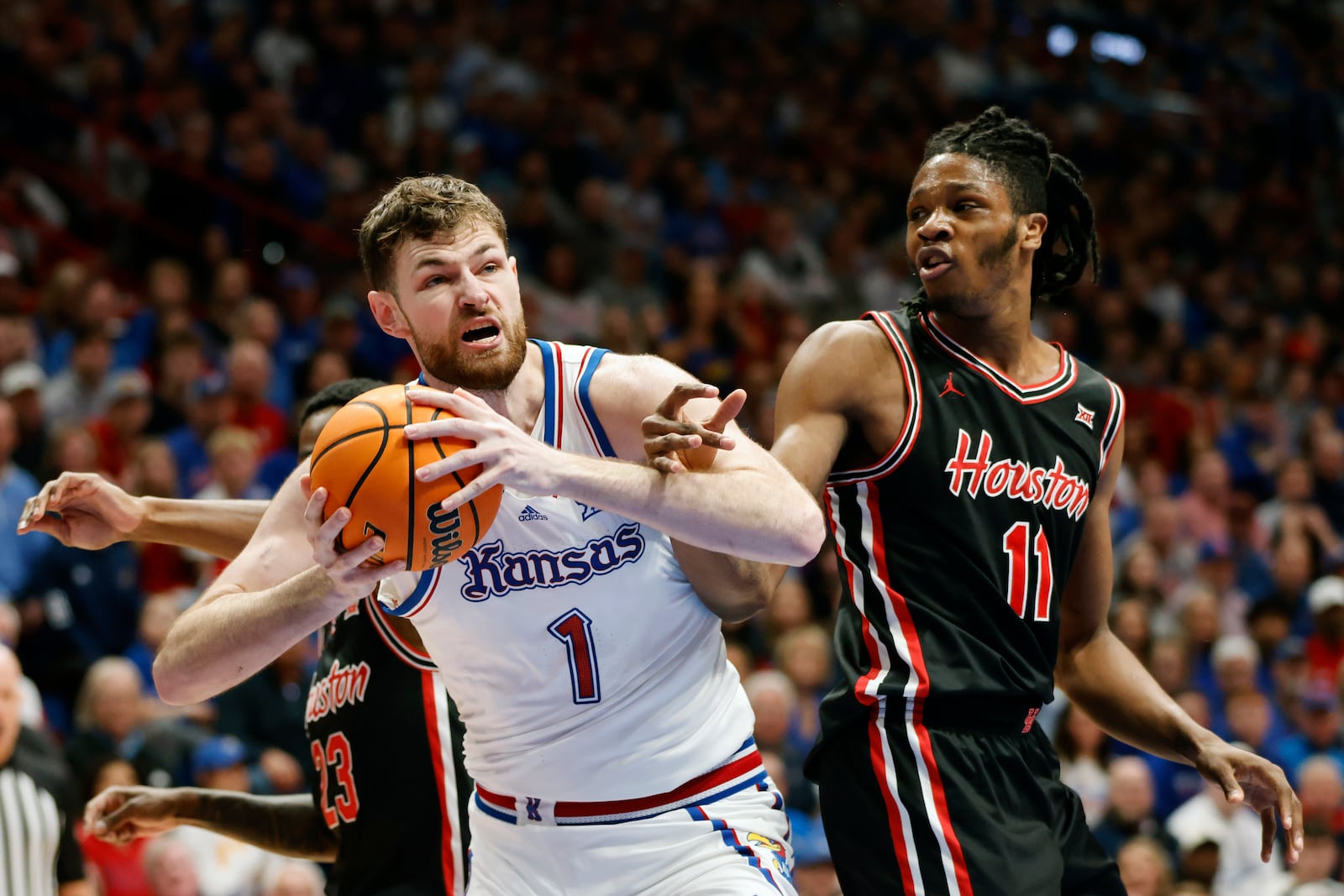 Kansas center Hunter Dickinson (1) is fouled by Houston forward Joseph Tugler (11) during the first half of an NCAA college basketball game, Saturday, Jan. 25, 2025, in Lawrence, Kan. (AP Photo/Colin E. Braley)