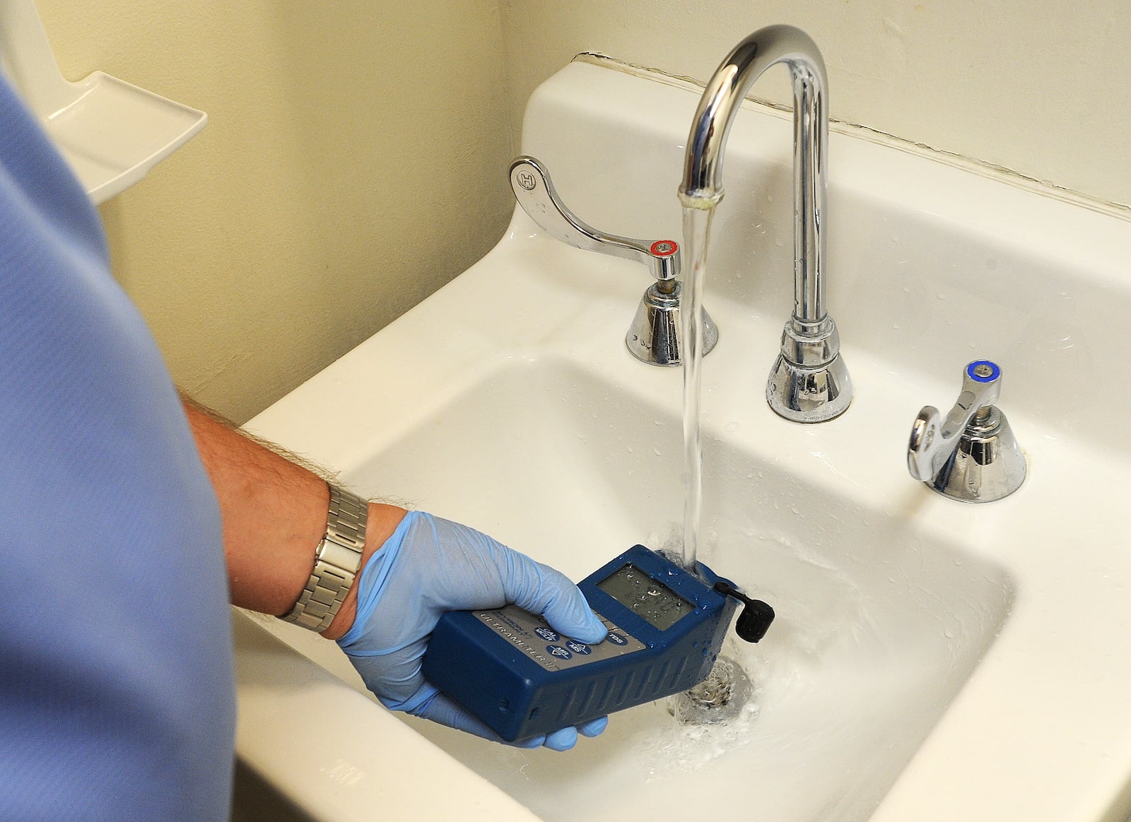 Doug Dolder, a Response Case Manager, for Solid Blend Water Management Solutions, test the water in a restroom at Southdale Elementary in Kettering for Legionella bacteria. MARSHALL GORBY\STAFF