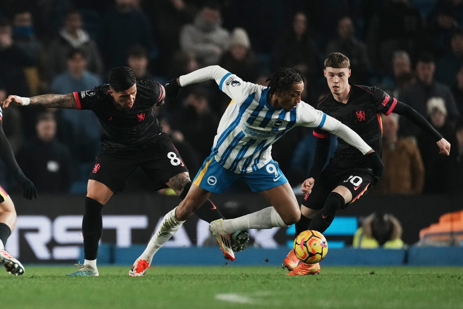 Brighton's Joao Pedro in action in front of Chelsea's Enzo Fernandez, left, and Cole Palmer during the English Premier League soccer match between Brighton and Chelsea in Brighton, England, Friday, Feb. 14, 2025. (AP Photo/Dave Shopland)