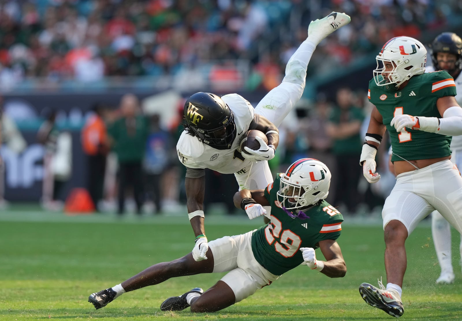 Wake Forest running back Demond Claiborne runs for a first down as Miami defensive back OJ Frederique Jr. (29) defends during the first half of an NCAA college football game, Saturday, Nov. 23, 2024, in Miami Gardens, Fla. (AP Photo/Lynne Sladky)