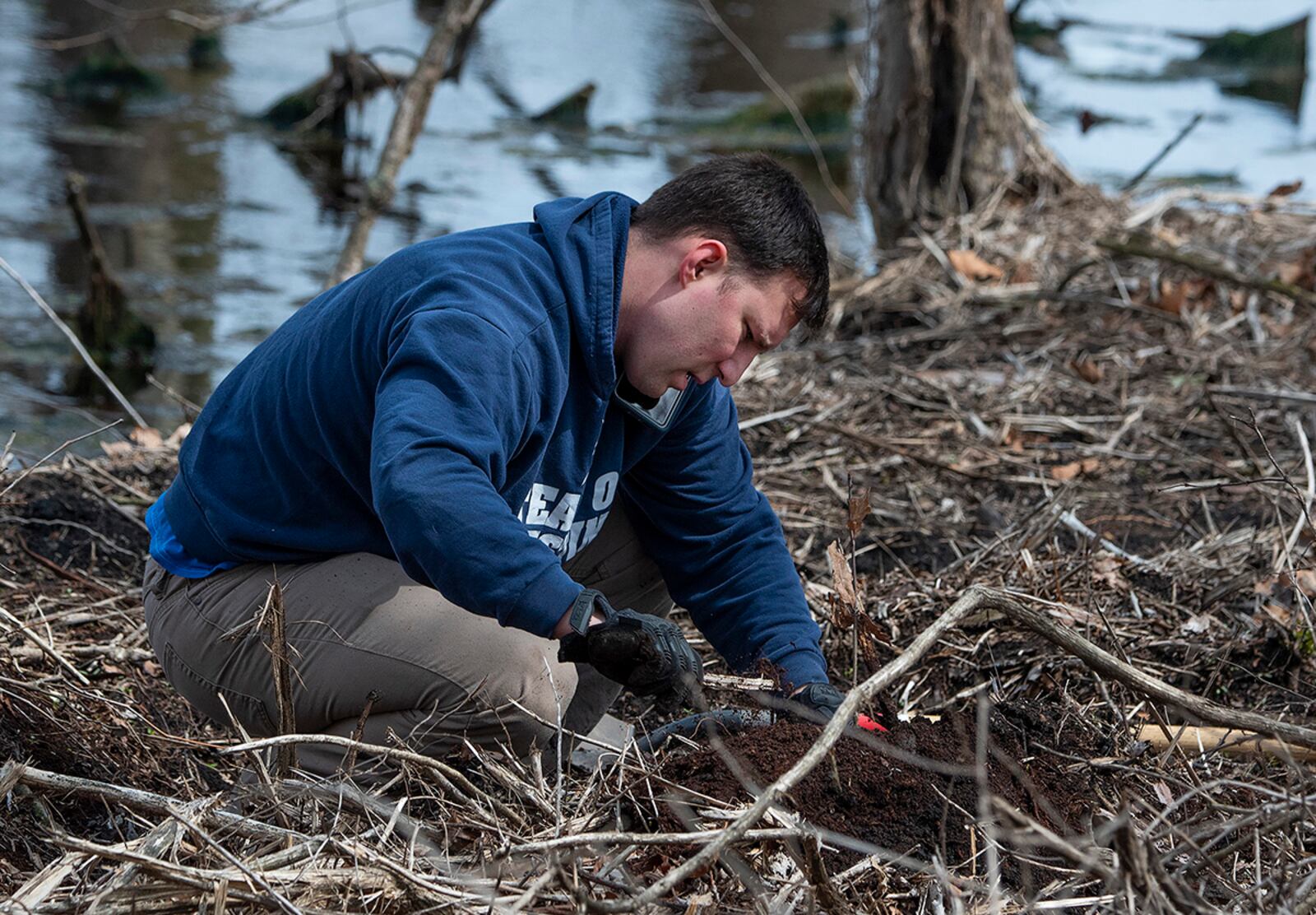 Staff Sgt. Paul Jezowski, 88th Security Forces Squadron, plants a seedling April 7 along Trout Creek on Wright-Patterson Air Force Base. A group of 88 SFS Defenders volunteered to help plant native-tree seedlings in an area recently cleared of invasive honeysuckle. U.S. AIR FORCE PHOTO/R.J. ORIEZ