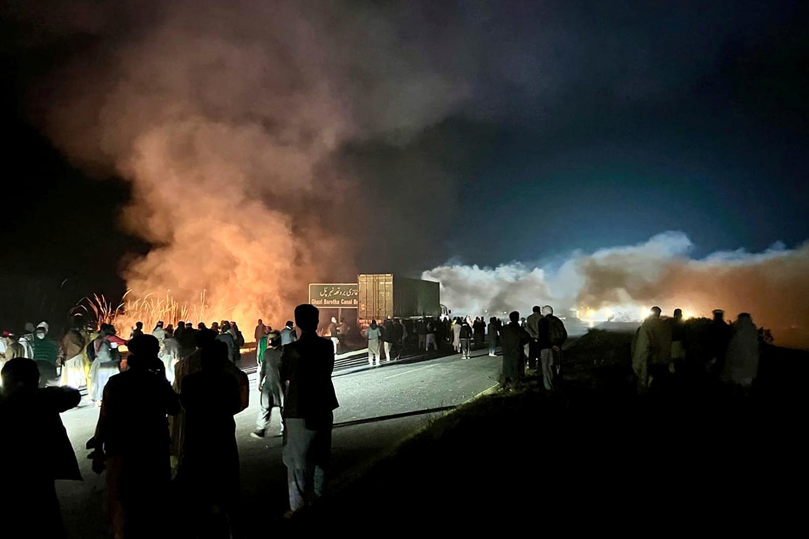 Supporters of imprisoned former premier Imran Khan's Pakistan Tehreek-e-Insaf party, burn bushes to reduce the impact of tear gas shells fired by police officers to disperse them during a rally demanding Khan's release, at a motorway in Ghazi in Attock district, Pakistan, Sunday, Nov. 24, 2024. (AP Photo/Maaz Awan)