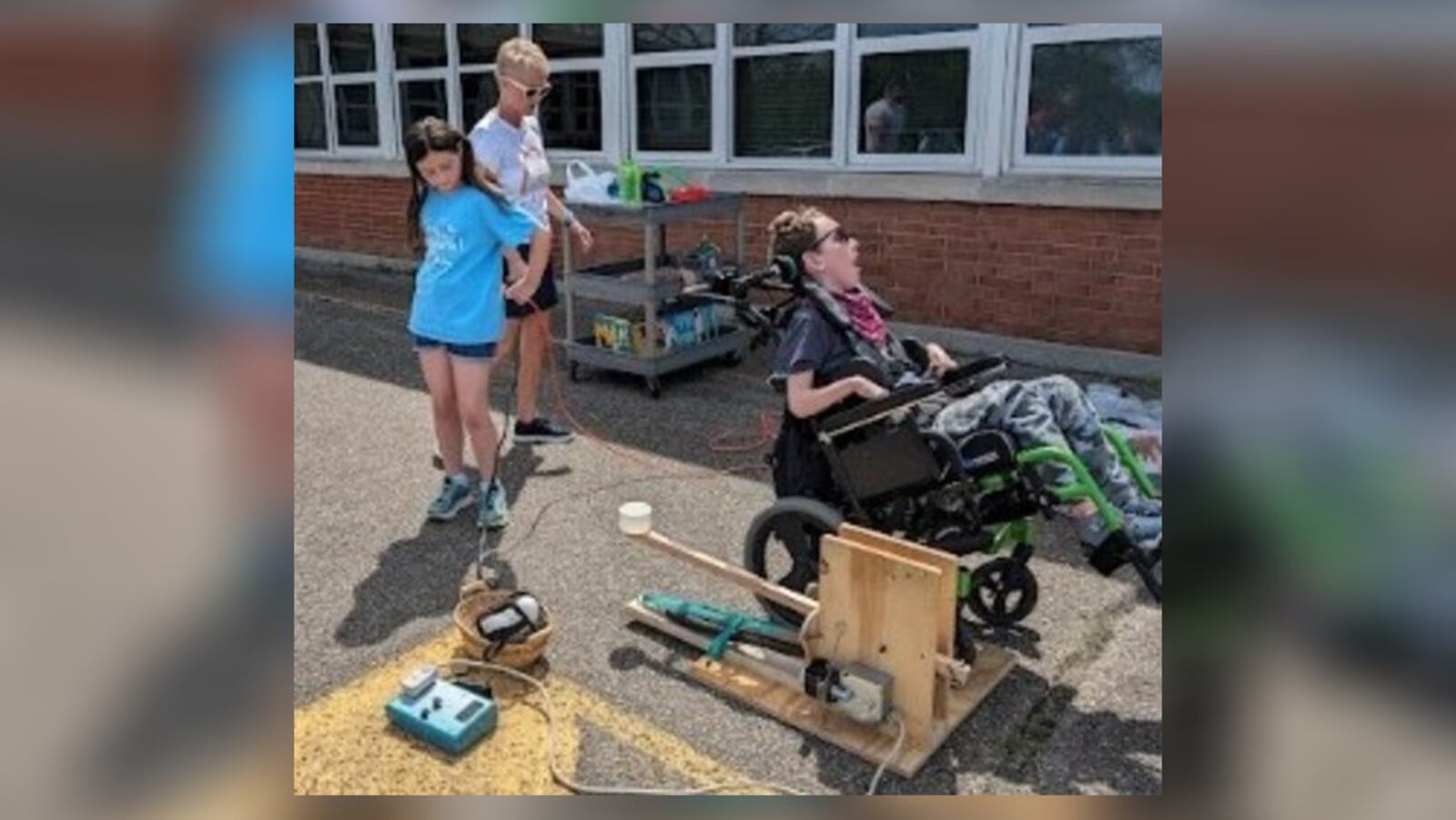 Two Kettering Prass Elementary School students – Lola and Neil – worked together to throw out the ceremonial first pitch at the Dayton Dragons game Friday night at Day Air Ballpark. Neil has cerebral palsy and experiences limited physical movement. With others helping, Lola designed a device that connects to Neil’s adaptive equipment so that he is able to throw a ball by activating a head switch. CONTRIBUTED