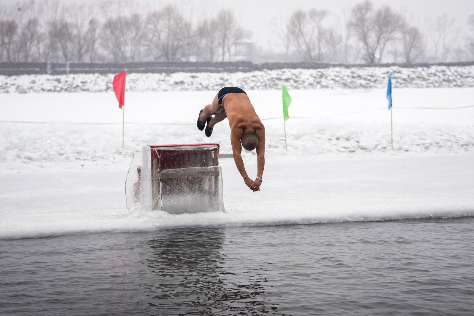 A man jumps into a pool carved from ice on the frozen Songhua river in Harbin in northeastern China's Heilongjiang province, Tuesday, Jan. 7, 2025. (AP Photo/Andy Wong)