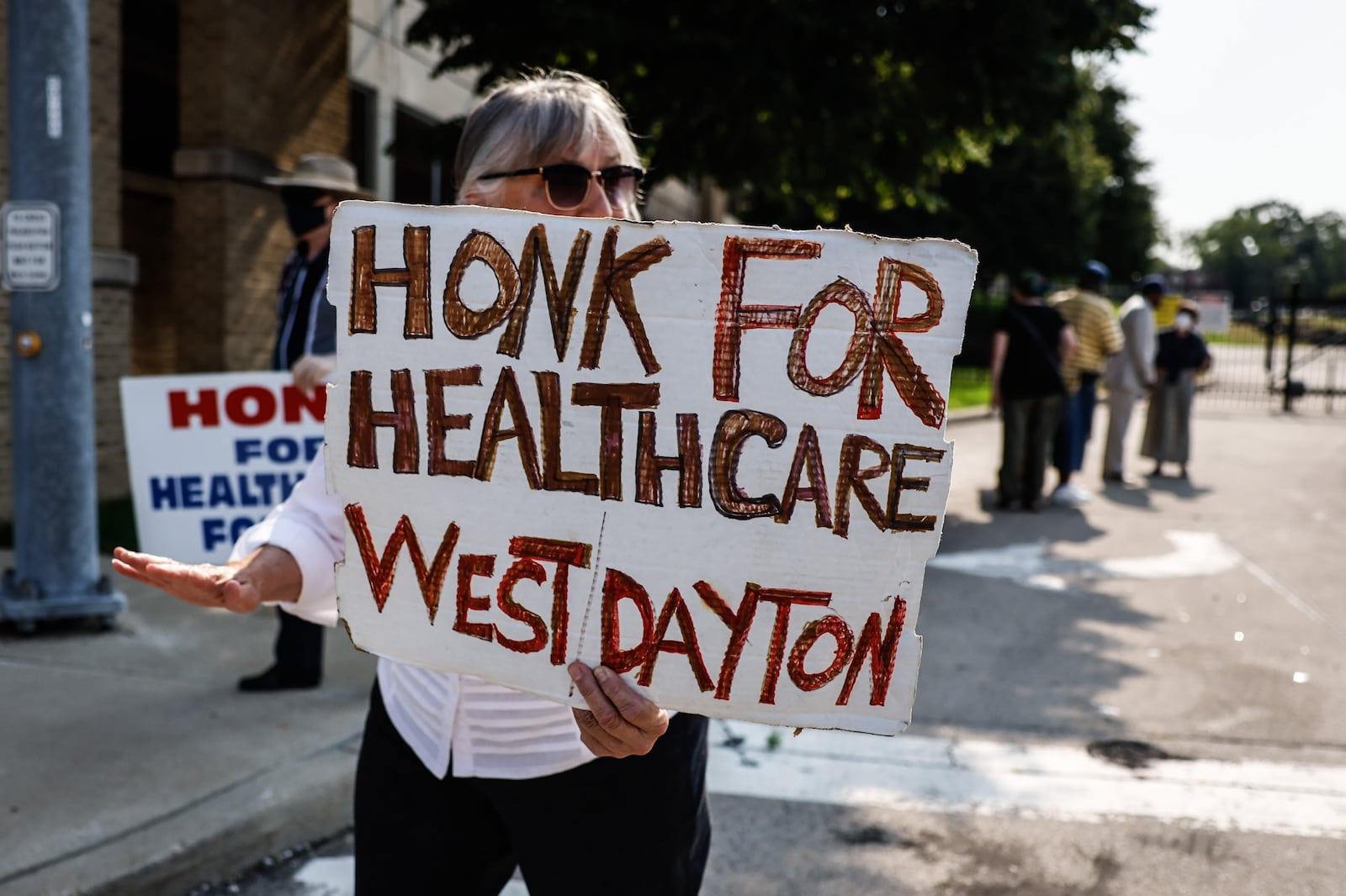 Kathleen Galt, from Dayton, along with other protesters carry signs near the site of the now demolished Good Sam Hospital Friday July 23, 2021. A press conference was held moments later where community leaders and clergy talked about Premier Health's plan to build an urgent care facility on the site. JIM NOELKER/STAFF