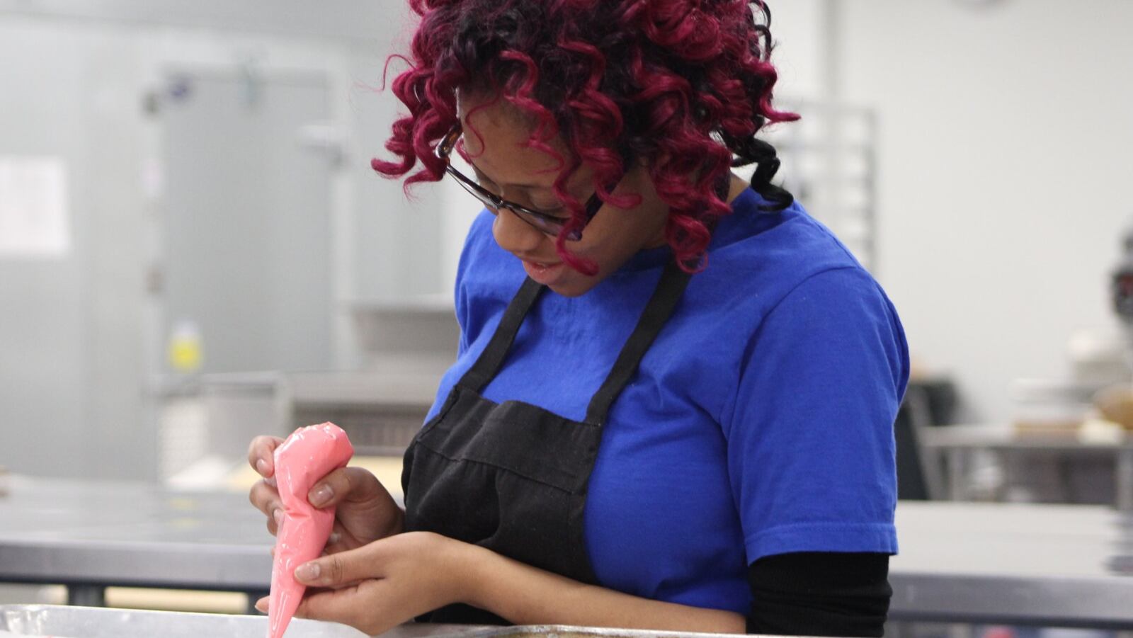 Shantel Hart, 23, decorates peanut butter and bacon dog treats for Valentine’s Day at Lindy & Company at 701 S. Patterson Blvd. The business sells 10 different types of gourmet dog treats. CORNELIUS FROLIK / STAFF