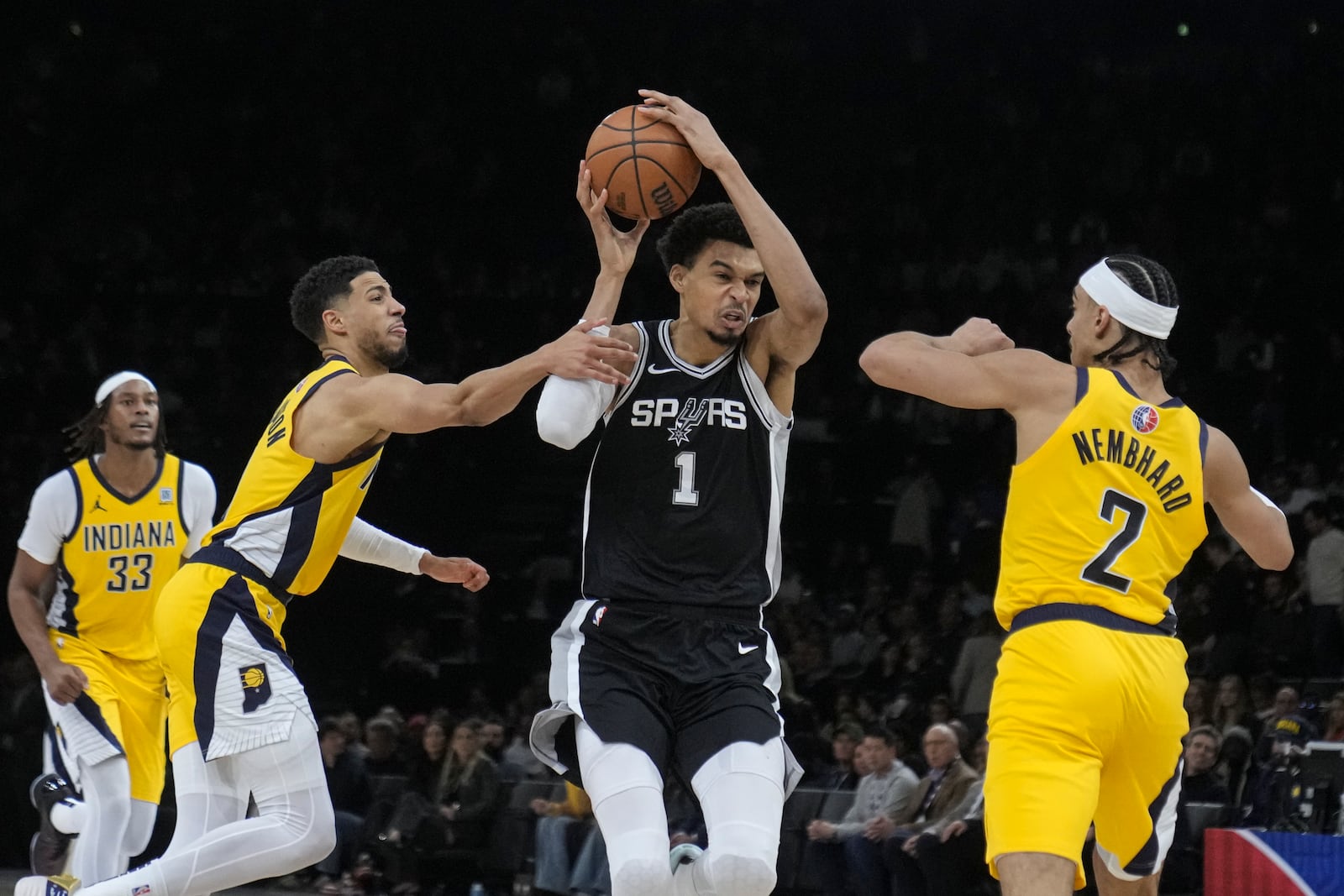 San Antonio Spurs center Victor Wembanyama (1) looks to shoot between Indiana Pacers guard Tyrese Haliburton (0) and guard Andrew Nembhard (2) during the second half of a Paris Games 2025 NBA basketball game in Paris, Saturday, Jan. 25, 2025. (AP Photo/Thibault Camus)