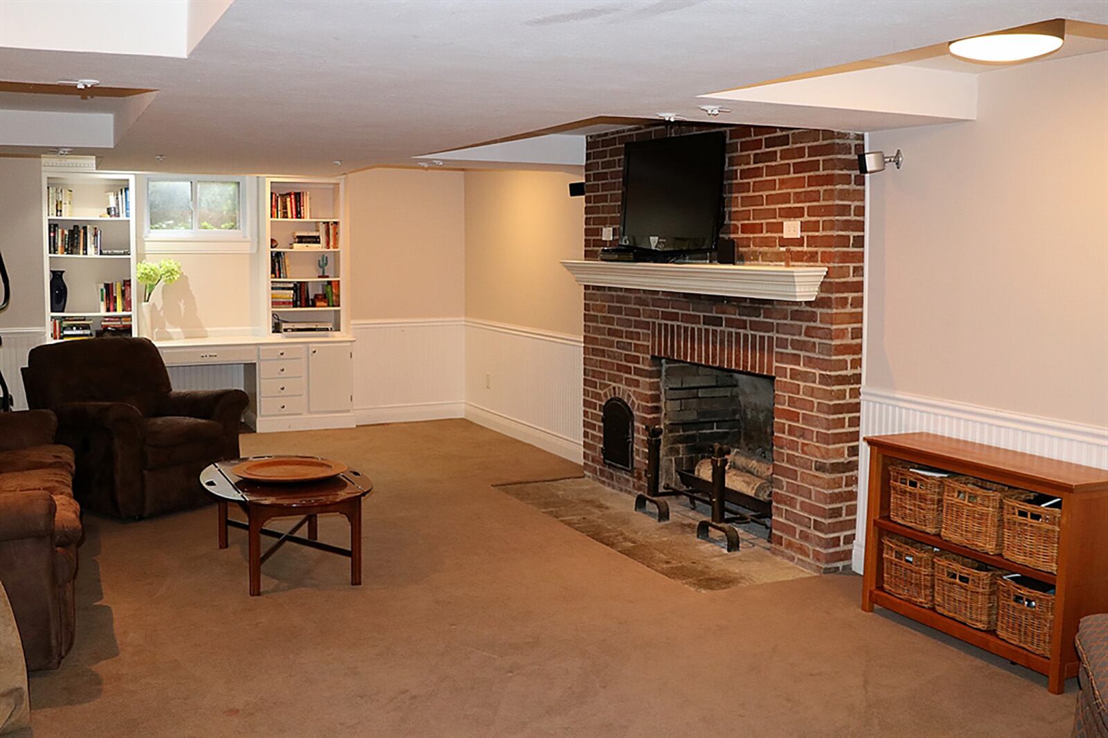 The basement has been finished into a recreation room with a brick, wood-burning fireplace with dentil wood mantel and wood box. Wainscotting accents the walls and complements the open bookcases that flank a window. CONTRIBUTED PHOTO BY KATHY TYLER